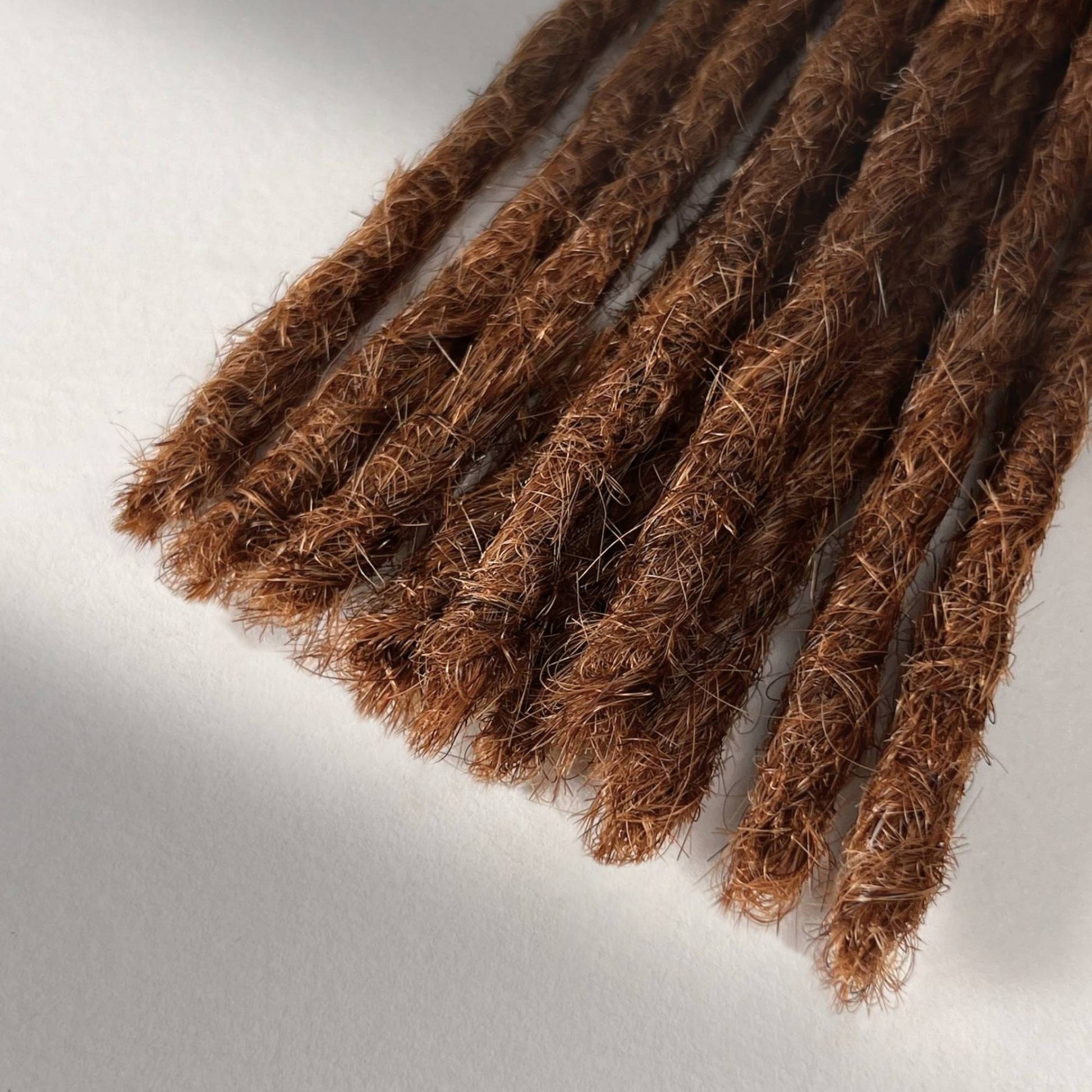 Tip detail of straight loc extensions with blunt ends in Burnt Sienna Copper.