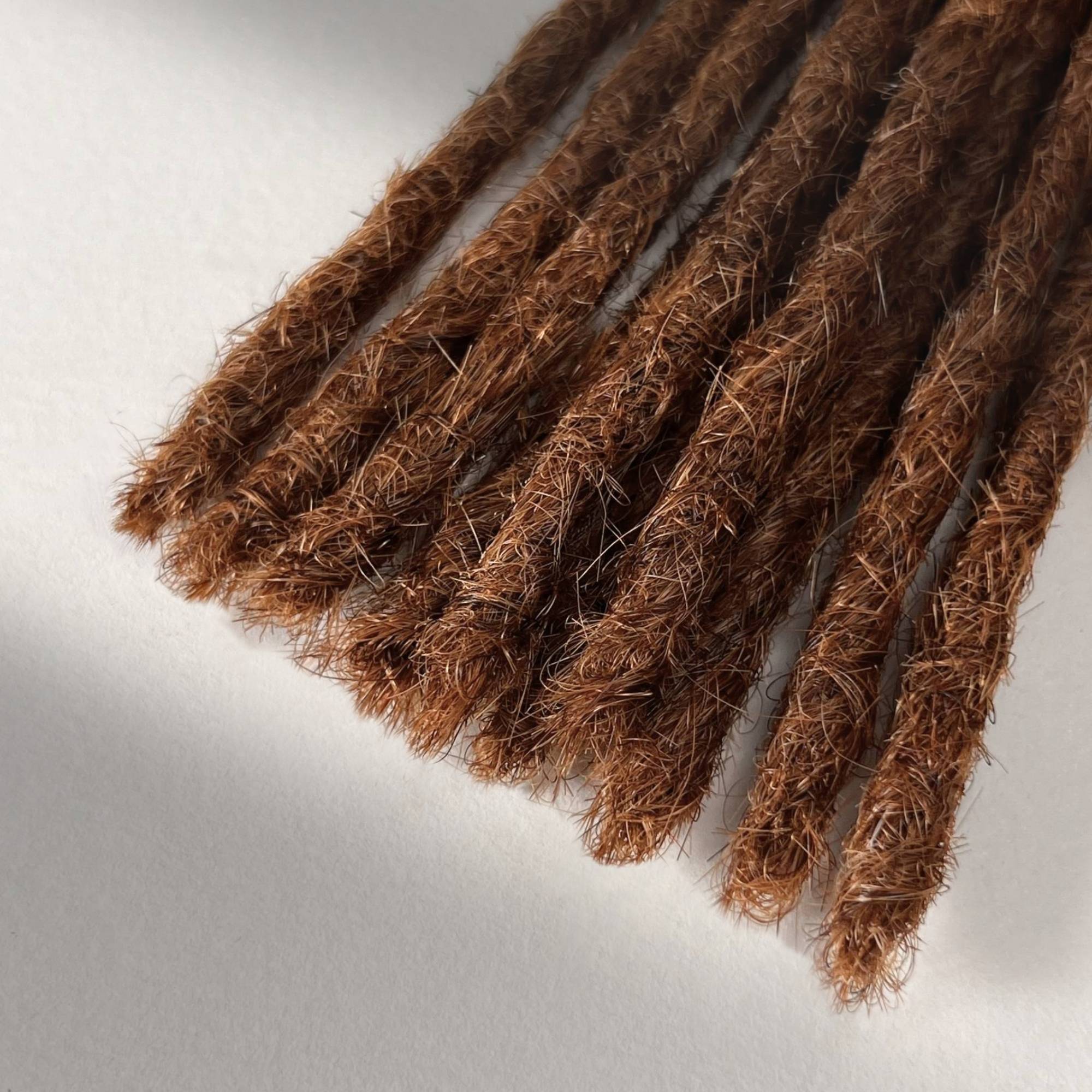 Tip detail of straight loc extensions with blunt ends in Burnt Sienna Copper.