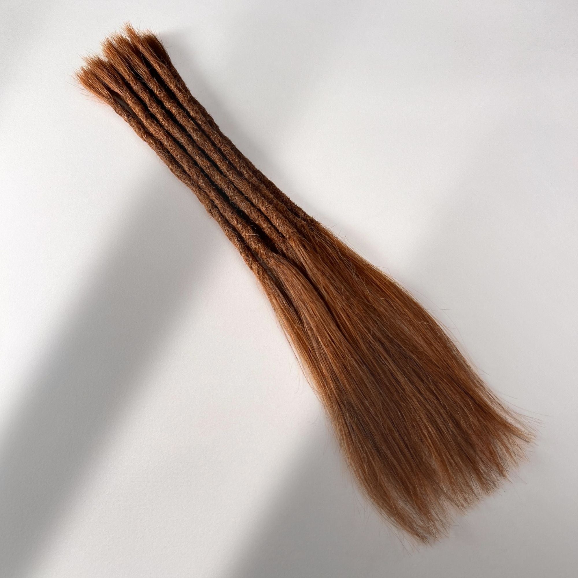 Full view of permanent straight loc extensions with long loose ends in Burnt Sienna Copper.