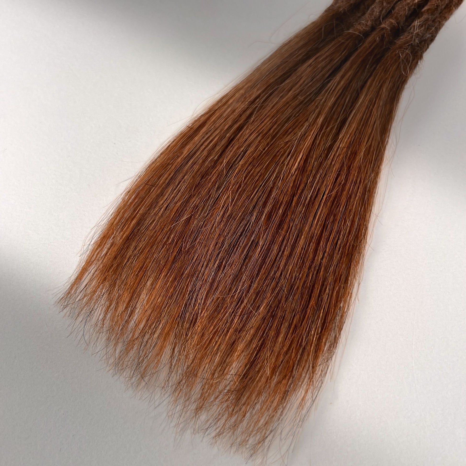 Tip detail of straight loc extensions with long loose ends in Burnt Sienna Copper.