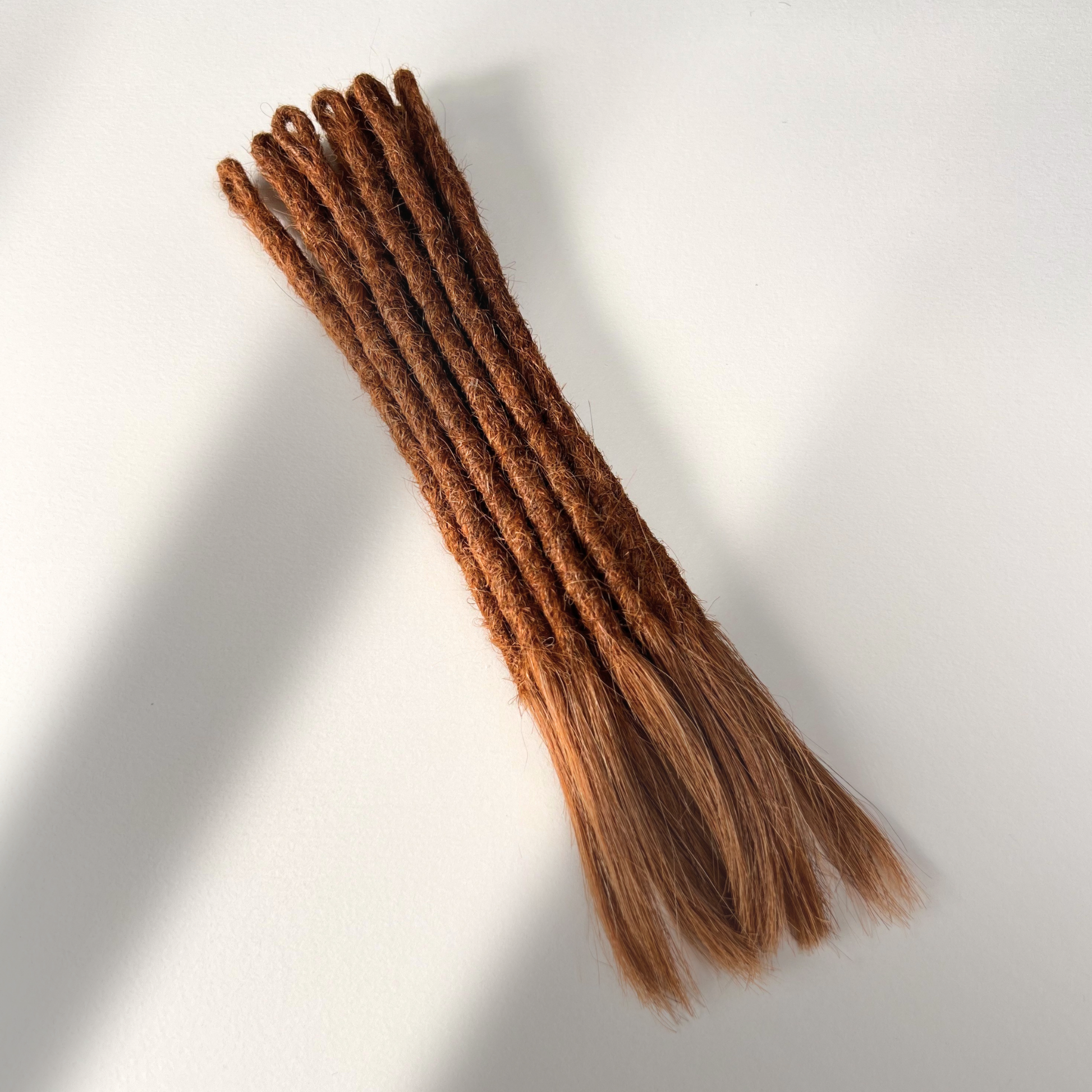 Full view of temporary single-ended straight loc extensions with open ends in Burnt Sienna Copper.