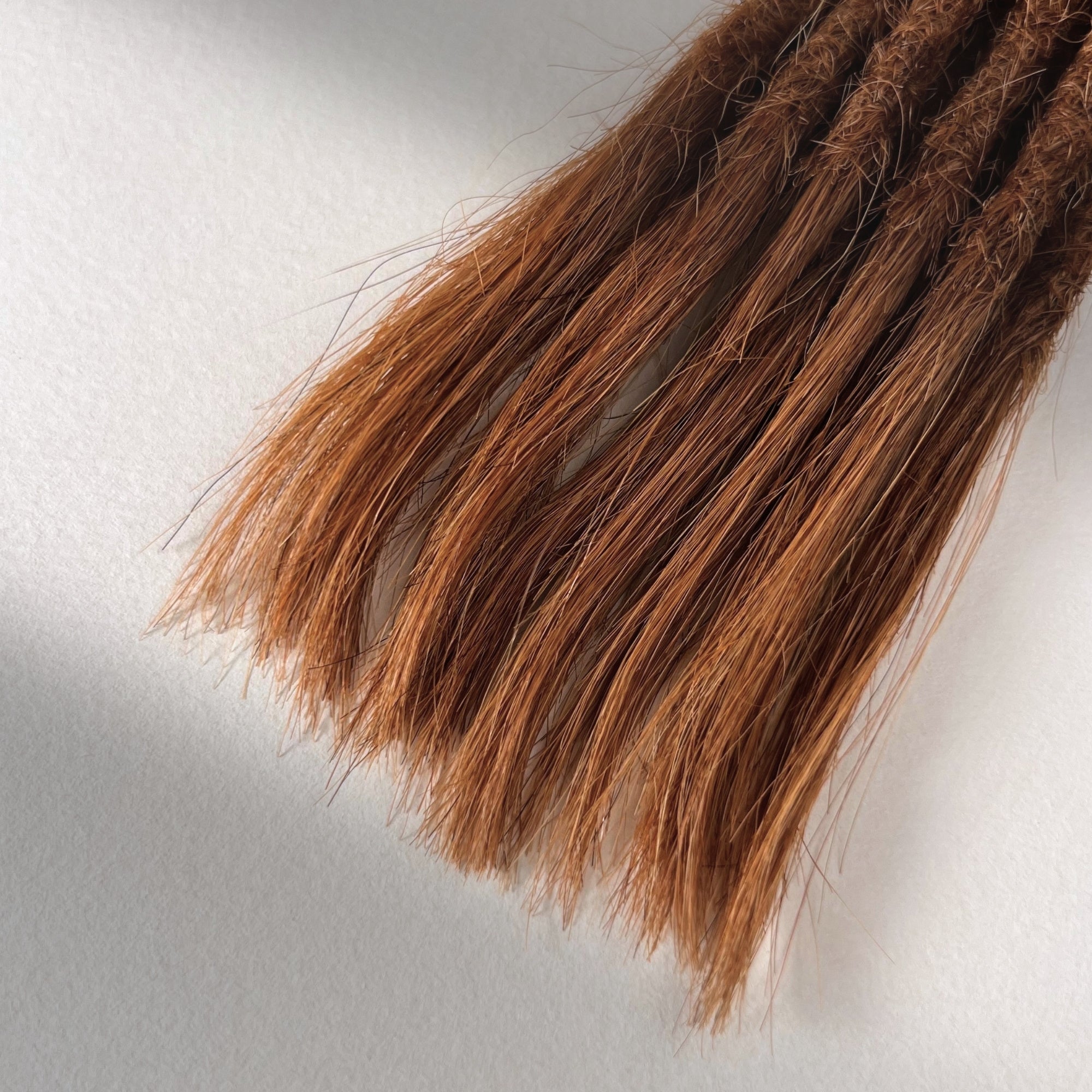 Tip detail of straight loc extensions with open ends in Burnt Sienna Copper.
