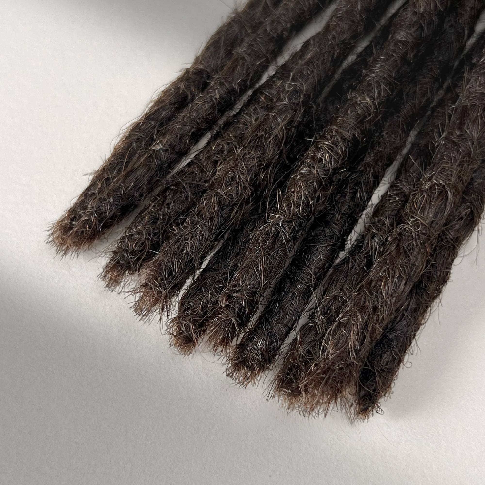 Tip detail of straight loc extensions with blunt ends in Warm Caramel Brown.