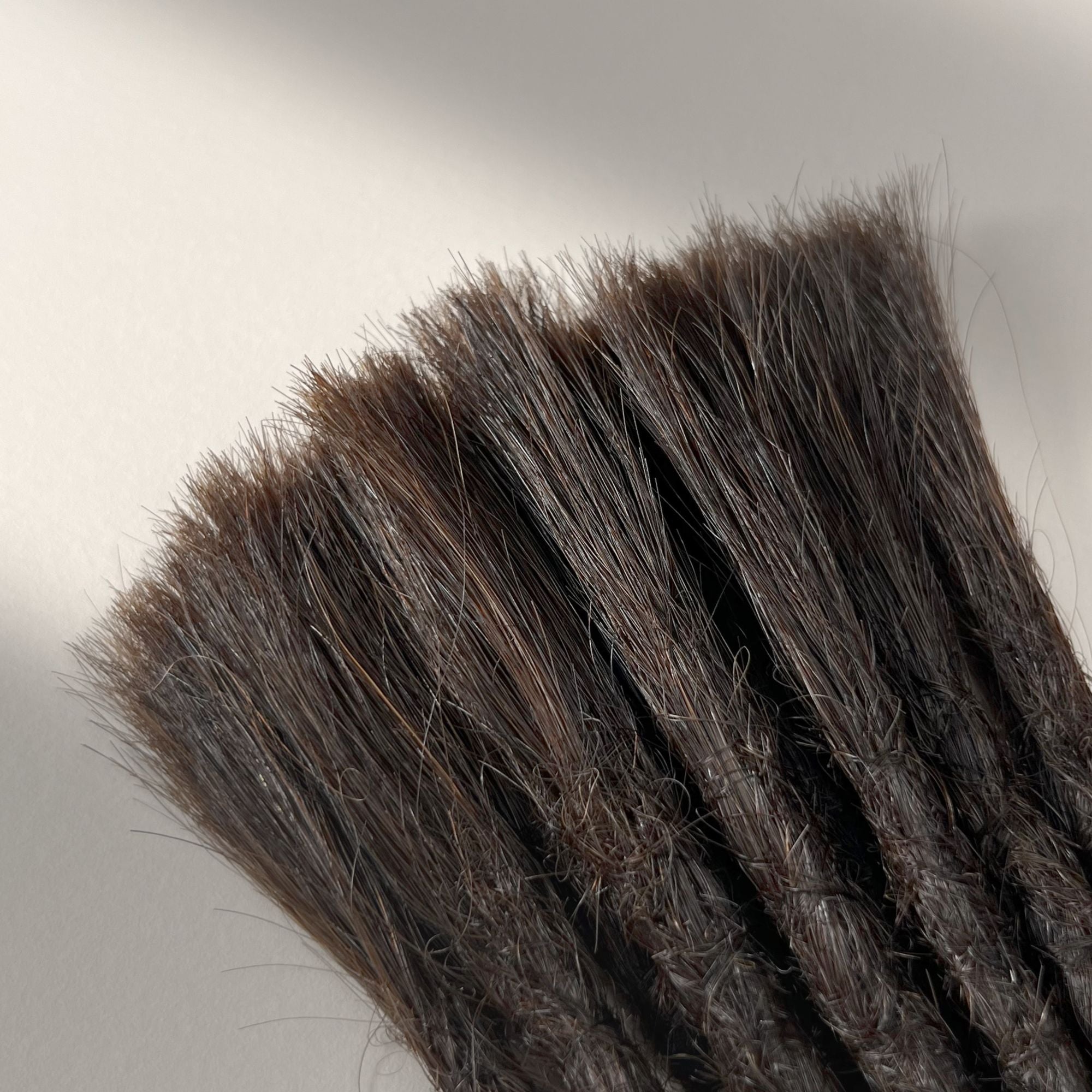 Connection point of permanent straight loc extensions with open ends in Warm Caramel Brown.
