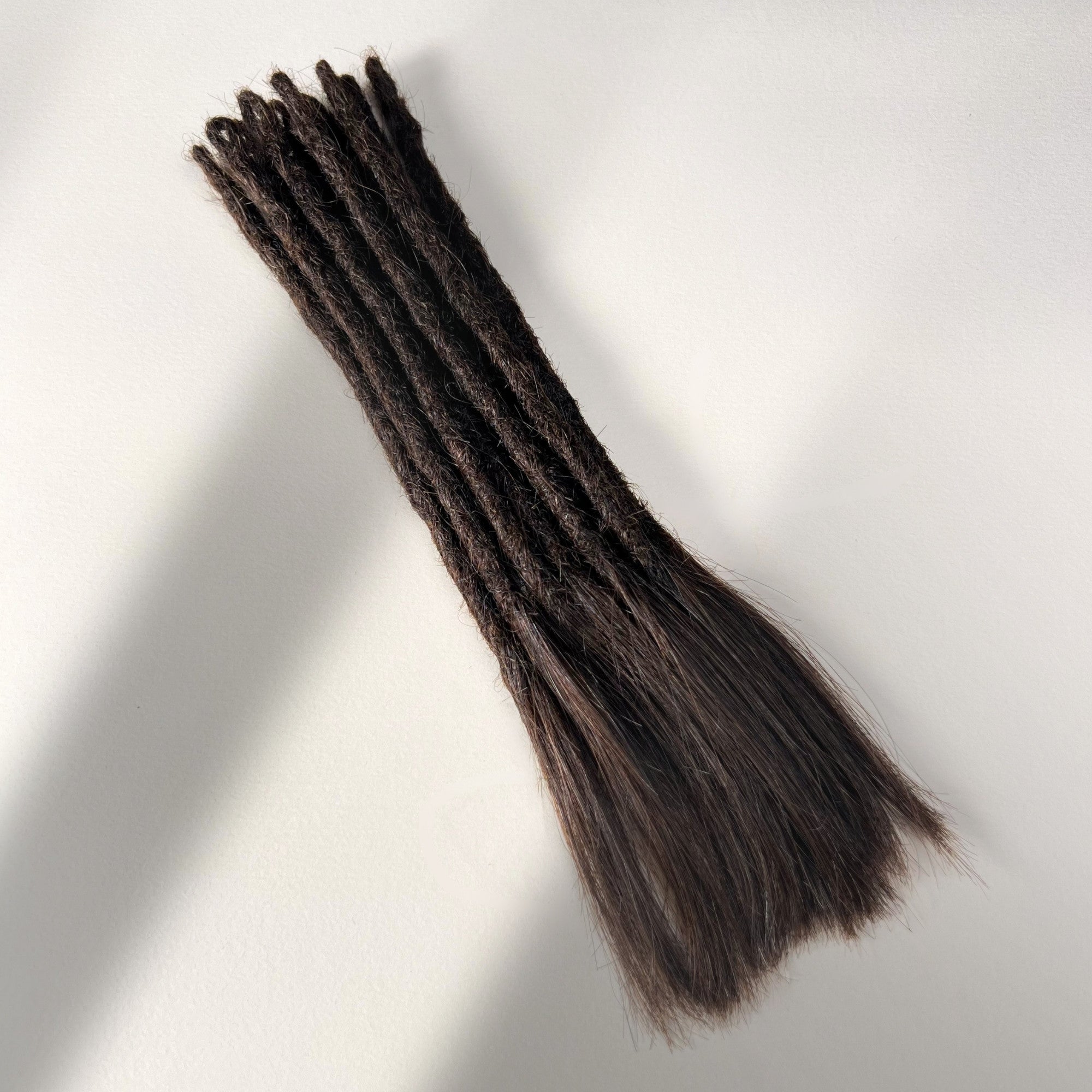 Full view of temporary single-ended straight loc extensions with open ends in Warm Caramel Brown.