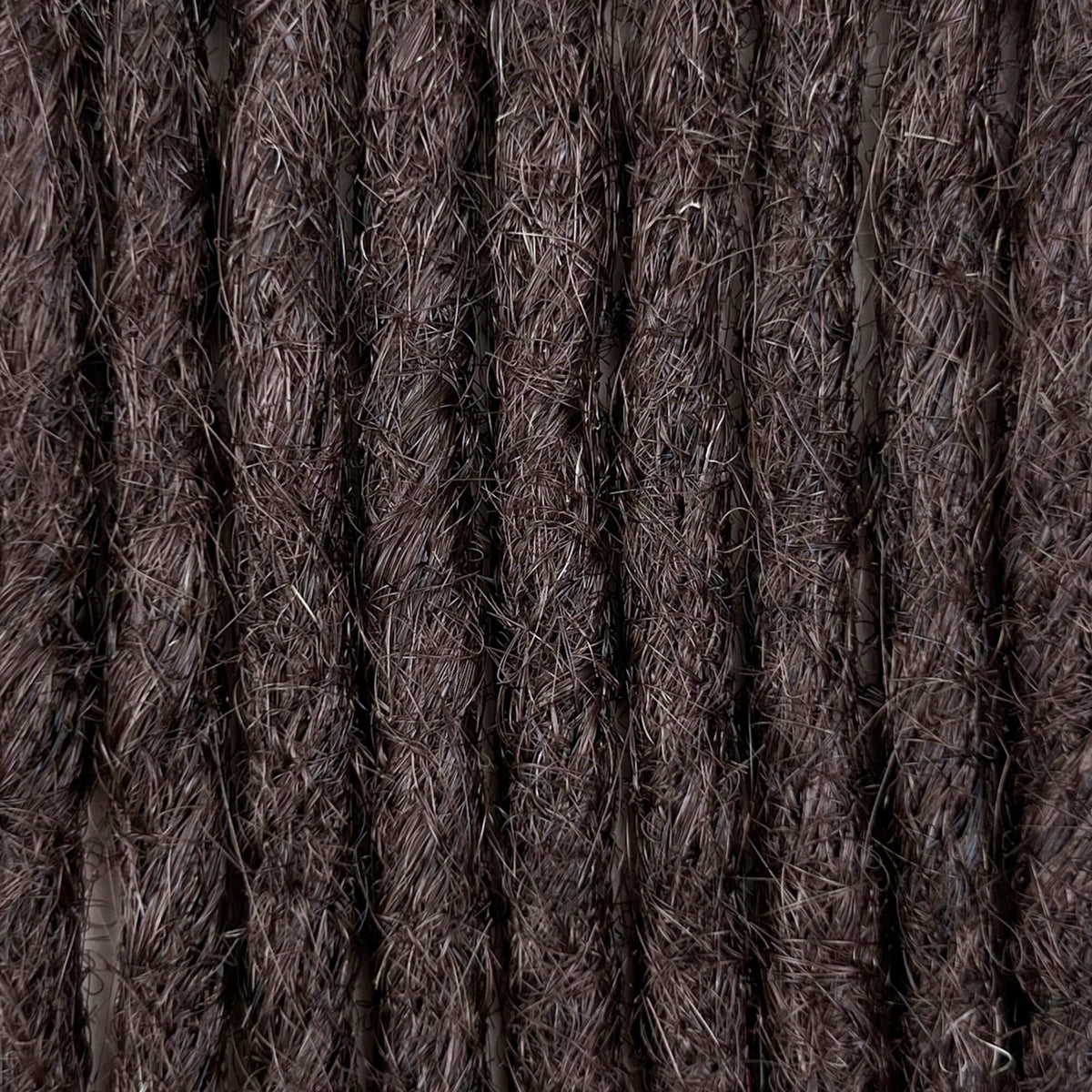 Close-up of straight loc extensions in Warm Caramel Brown, showing the texture and color.