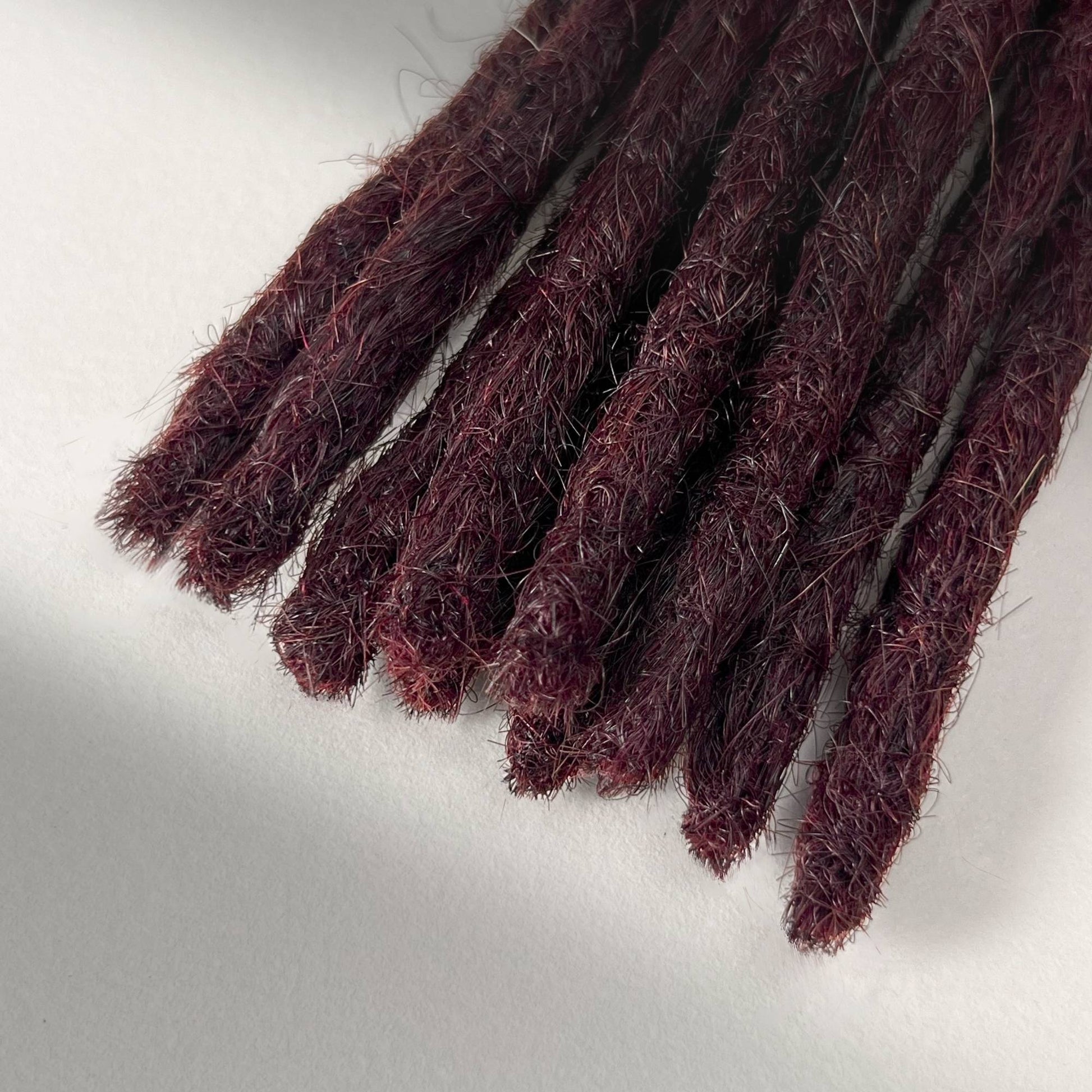 Tip detail of straight loc extensions with blunt ends in Deep Crimson Red.