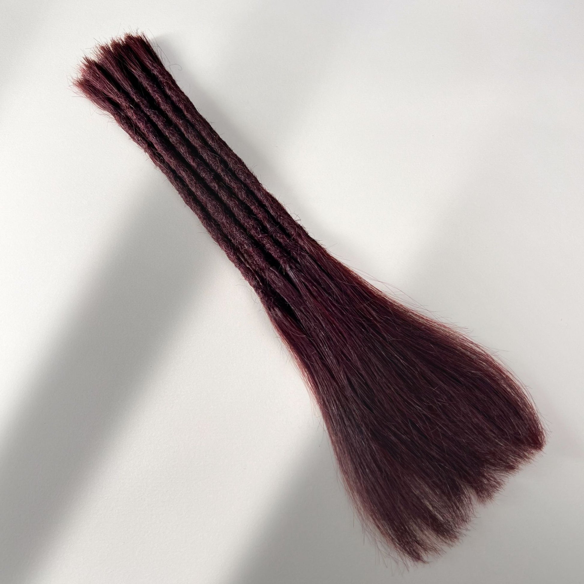 Full view of permanent straight loc extensions with long loose ends in Deep Crimson Red.