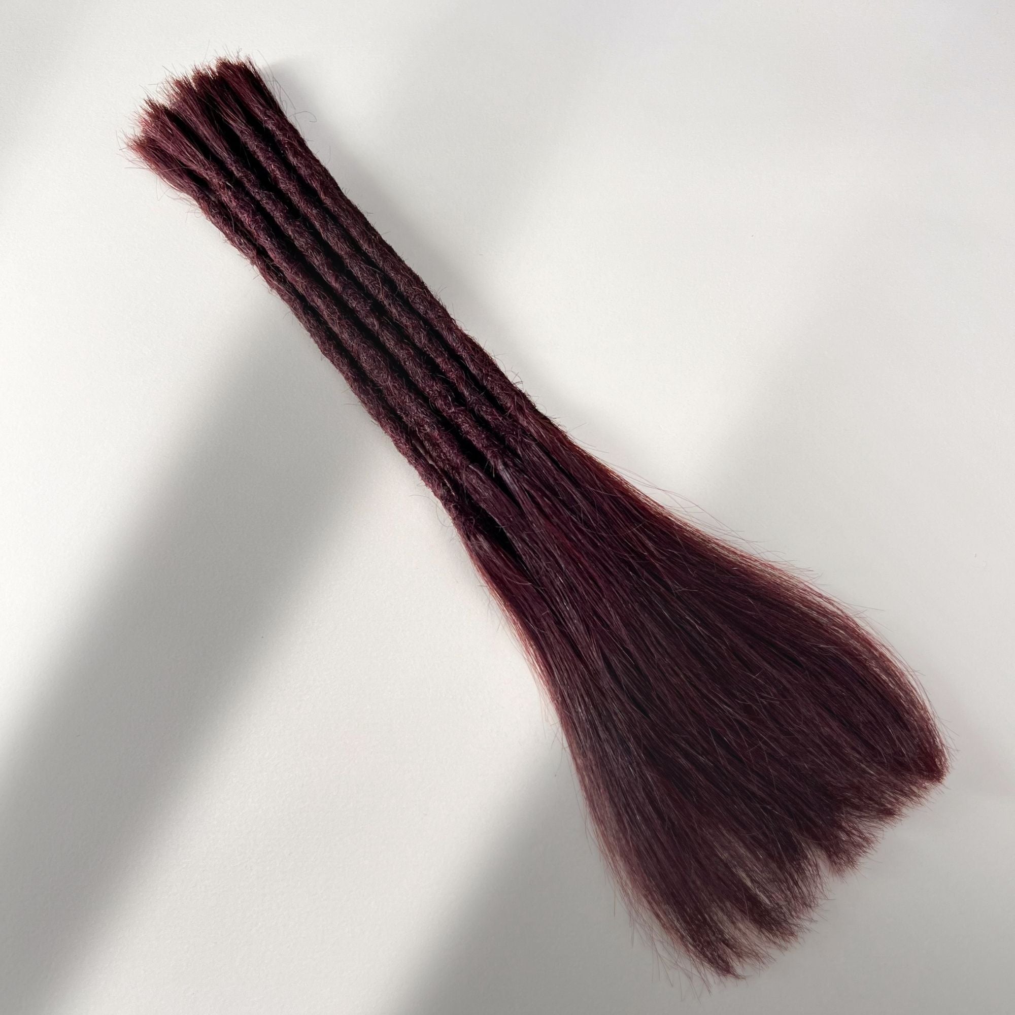 Full view of permanent straight loc extensions with long loose ends in Deep Crimson Red.