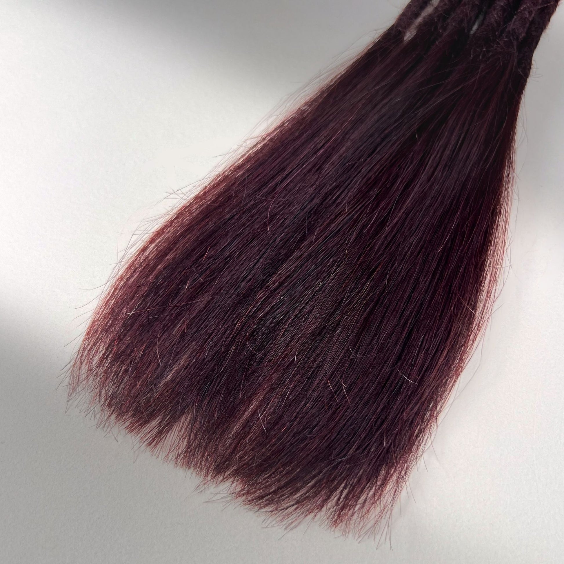 Tip detail of straight loc extensions with long loose ends in Deep Crimson Red.