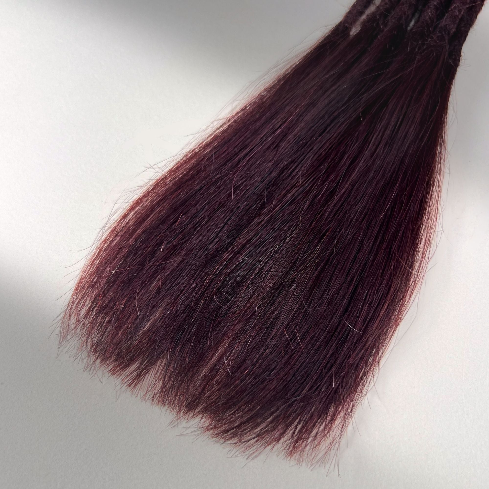 Tip detail of straight loc extensions with long loose ends in Deep Crimson Red.