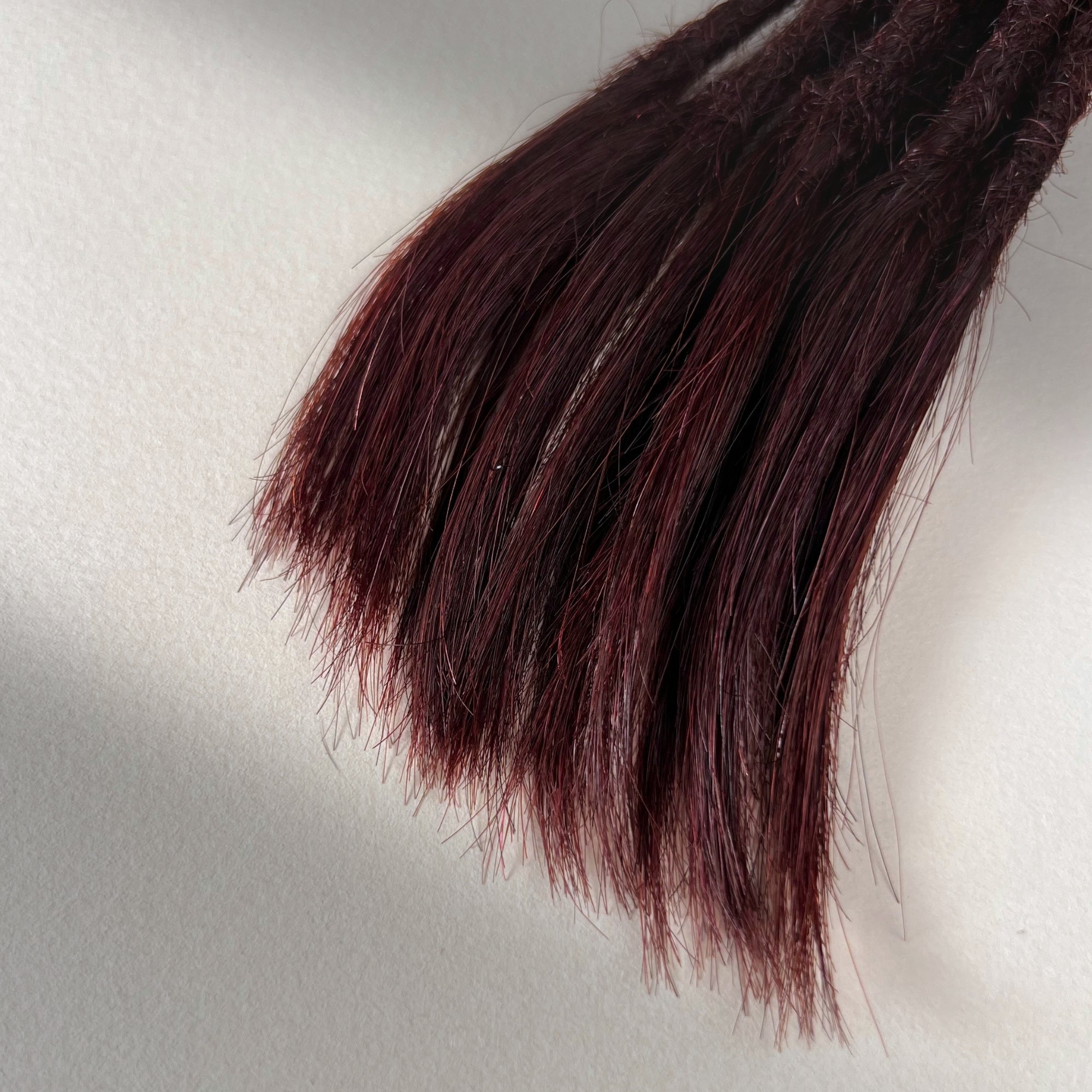Tip detail of straight loc extensions with open ends in Deep Crimson Red.