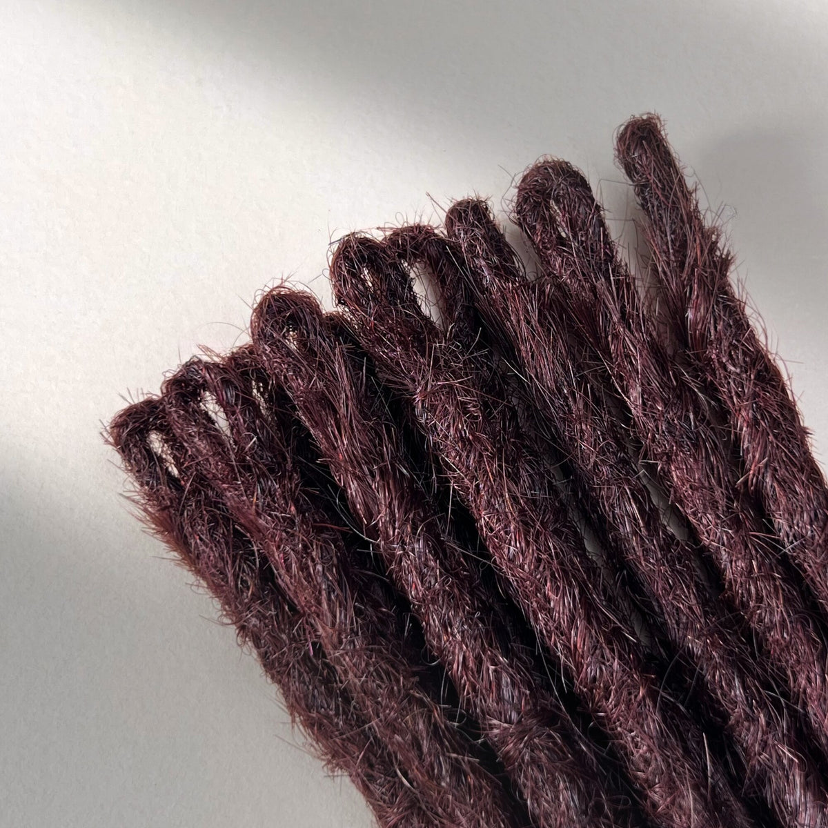 Loop detail of temporary single-ended straight loc extensions in Deep Crimson Red.