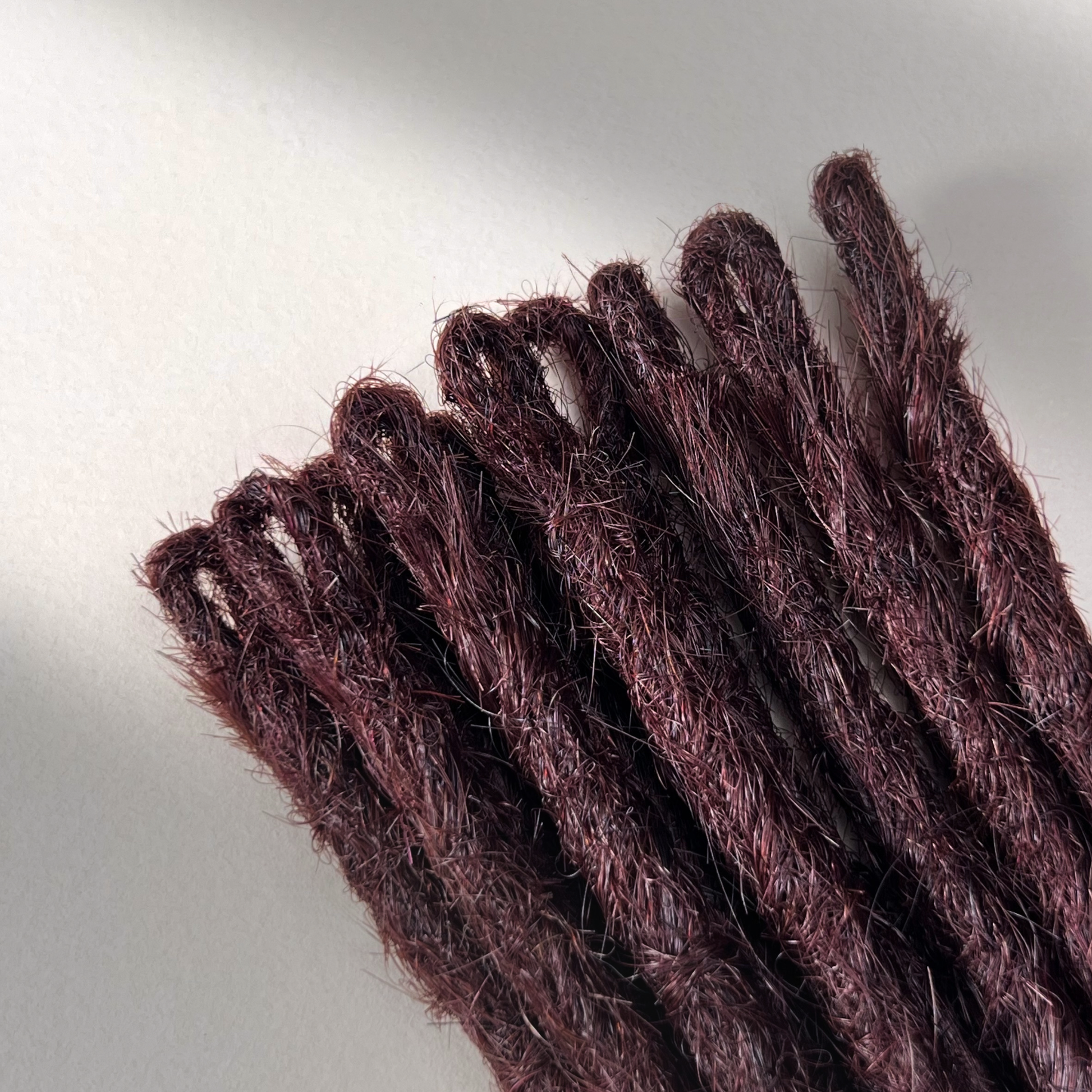 Loop detail of temporary single-ended straight loc extensions in Deep Crimson Red.