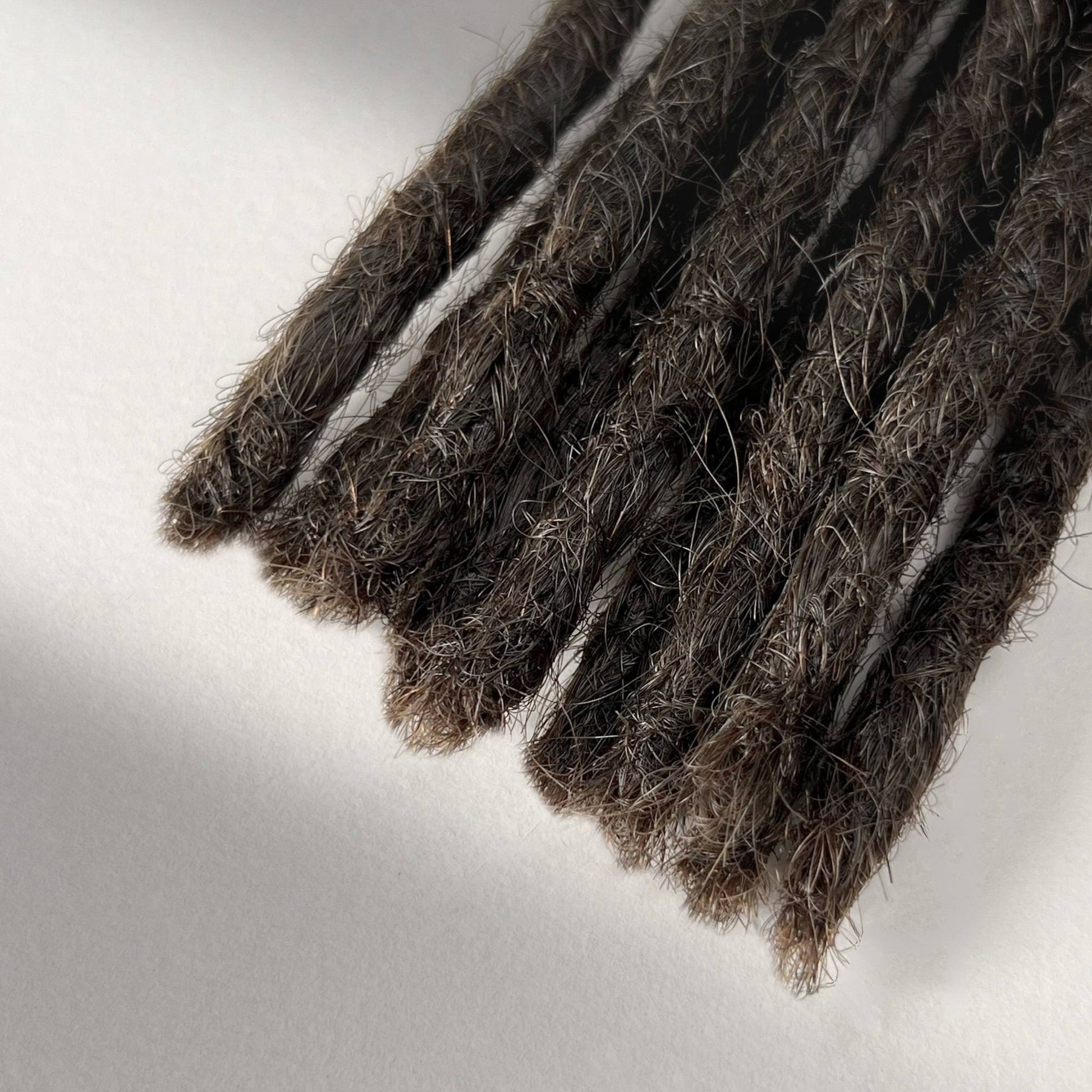 Tip detail of straight loc extensions with blunt ends in Dark Wenge Brown.