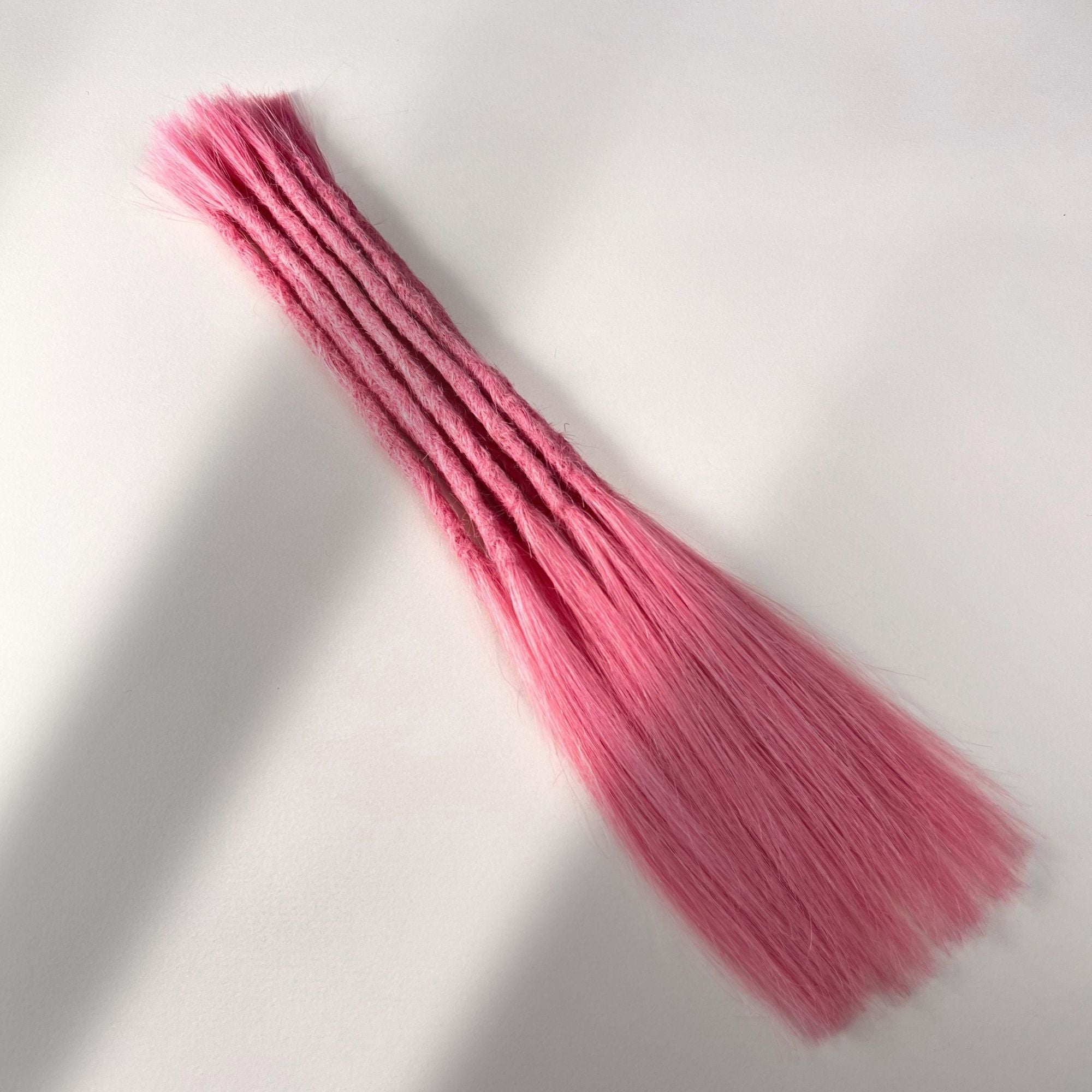 Full view of permanent straight loc extensions with long loose ends in Bubblegum Pink.