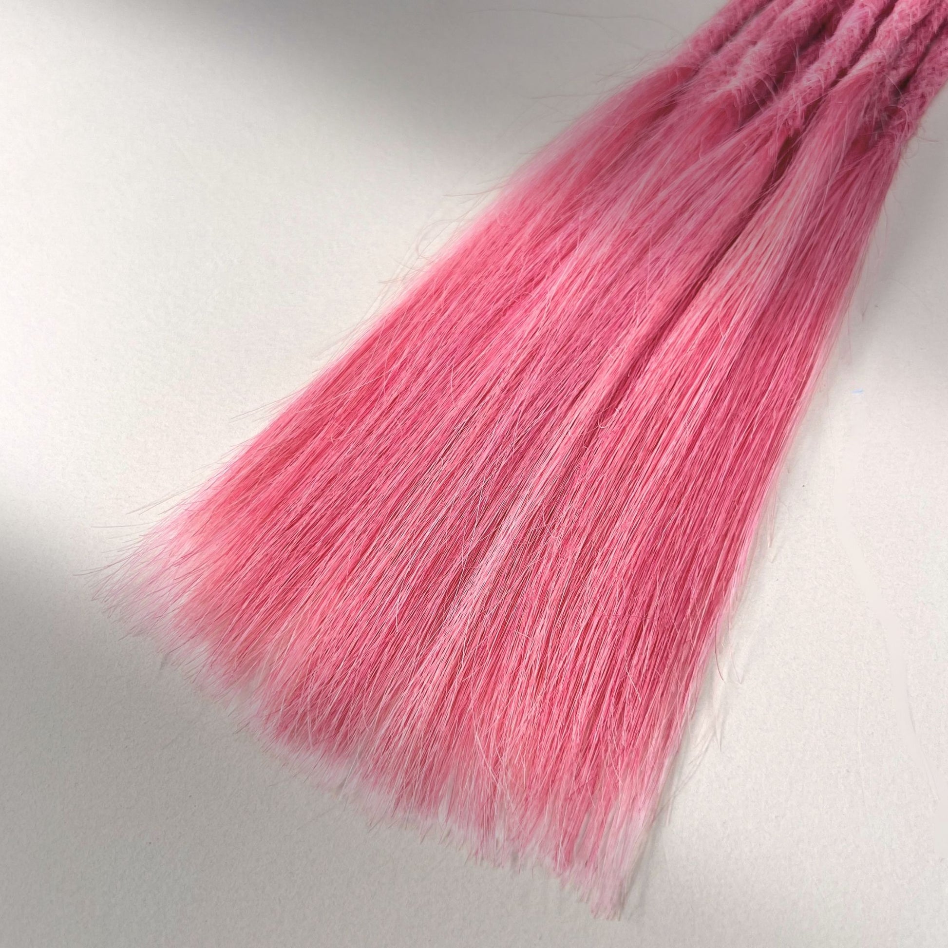 Tip detail of straight loc extensions with long loose ends in Bubblegum Pink.