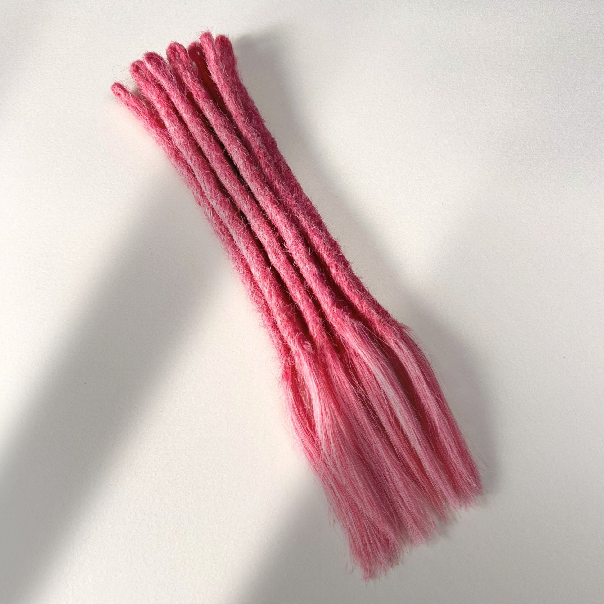 Full view of temporary single-ended straight loc extensions with open ends in Bubblegum Pink.