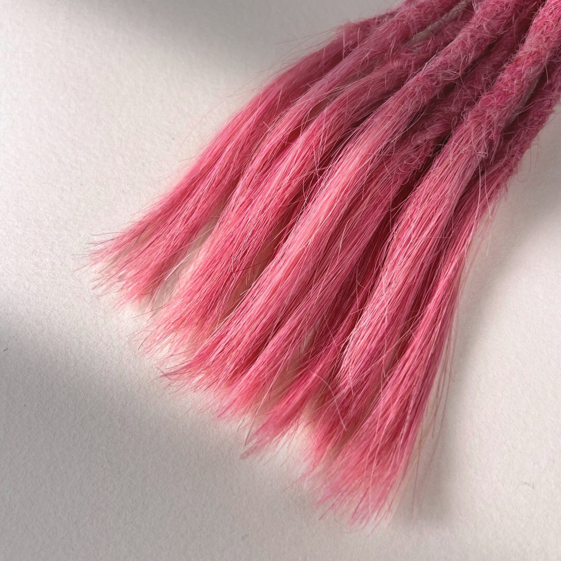 Tip detail of straight loc extensions with open ends in Bubblegum Pink.