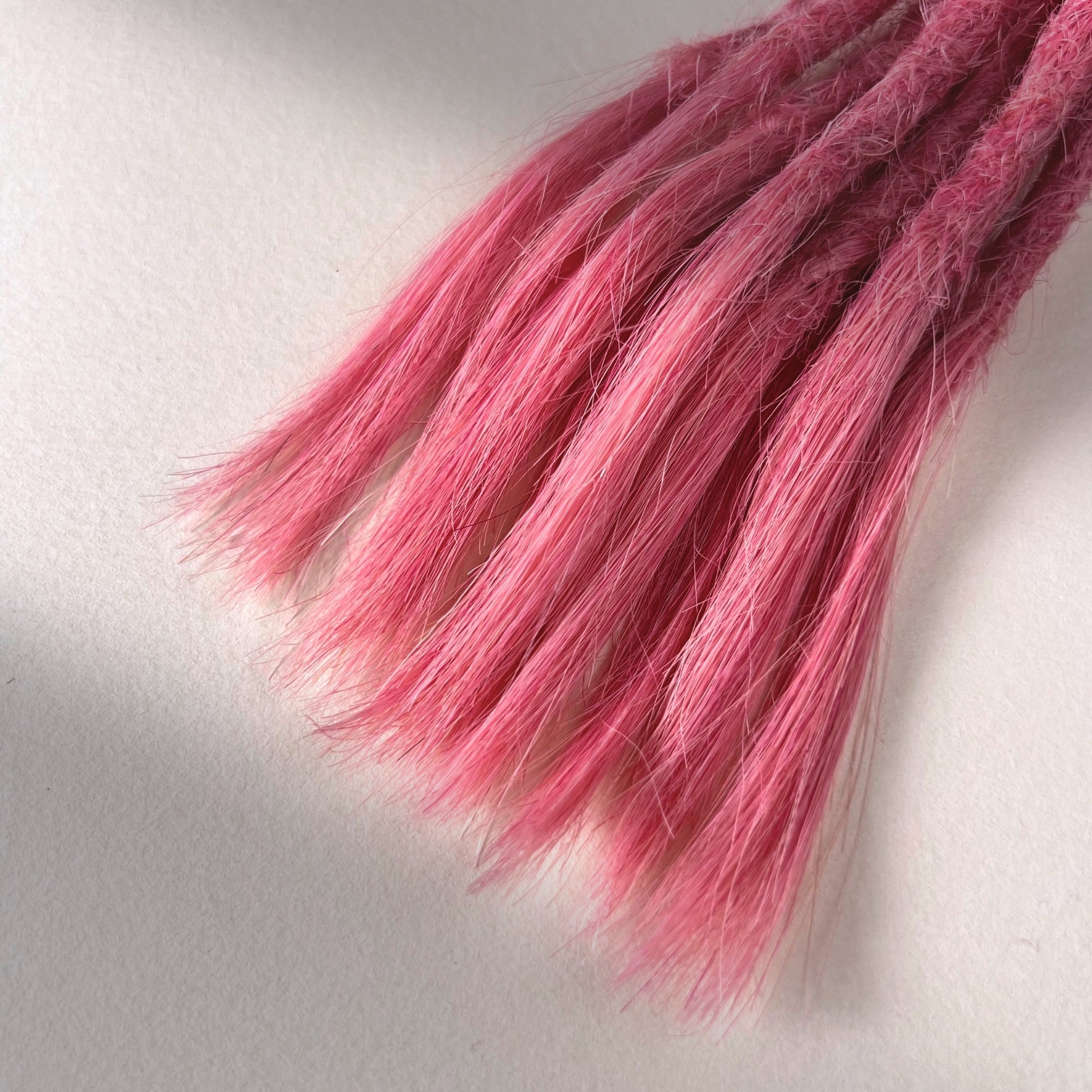 Tip detail of straight loc extensions with open ends in Bubblegum Pink.