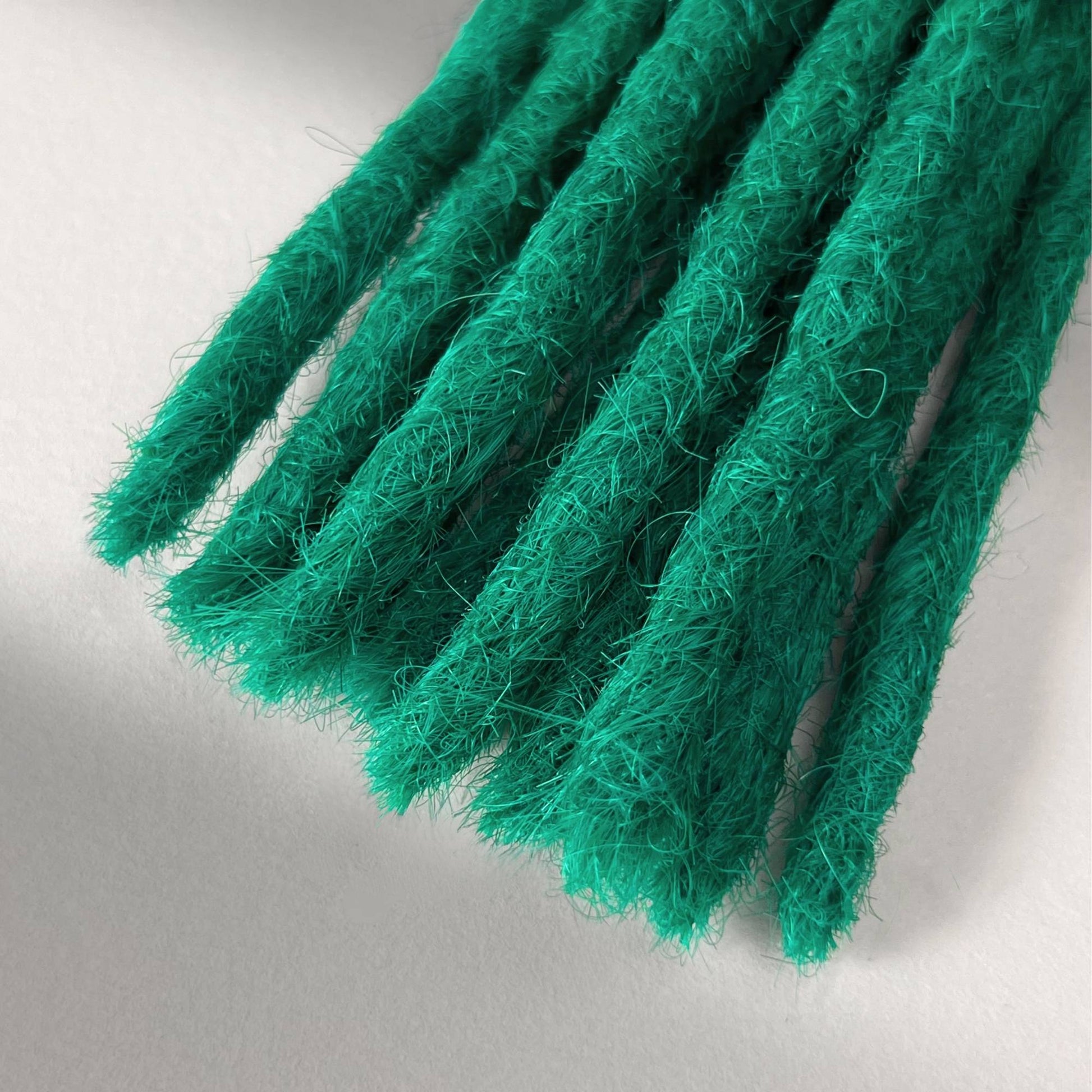 Tip detail of straight loc extensions with blunt ends in Emerald Green.