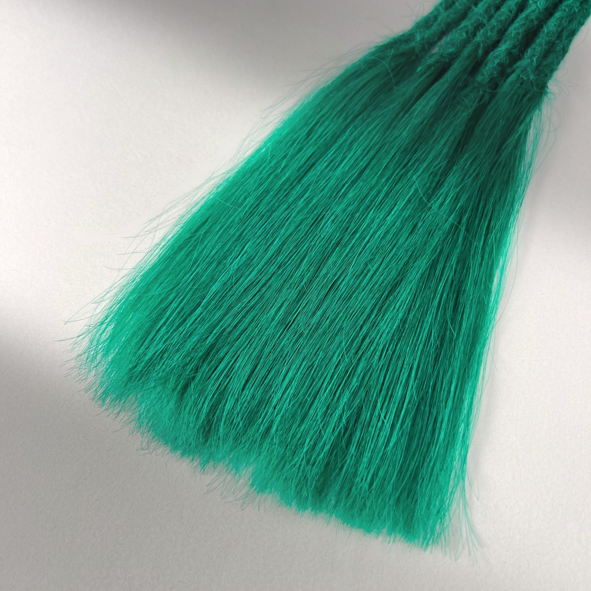 Tip detail of straight loc extensions with long loose ends in Emerald Green.