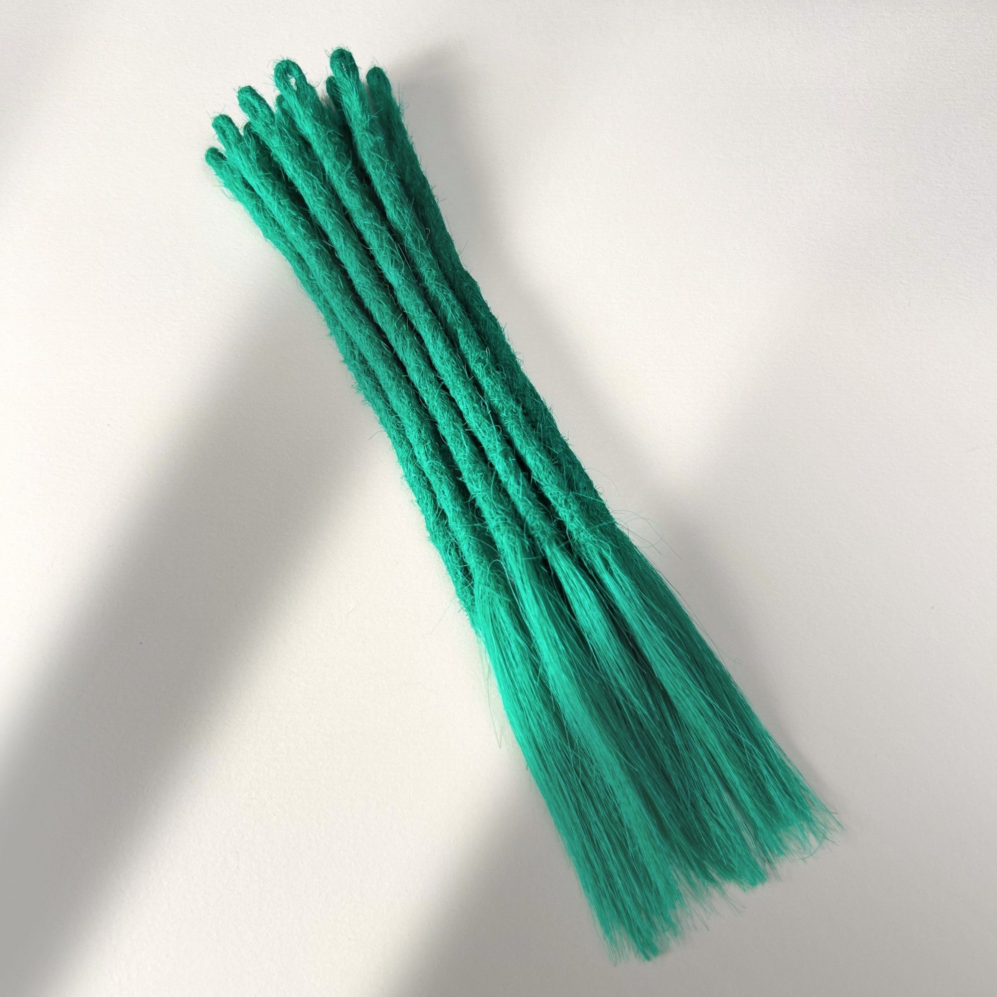 Full view of temporary single-ended straight loc extensions with open ends in Emerald Green.