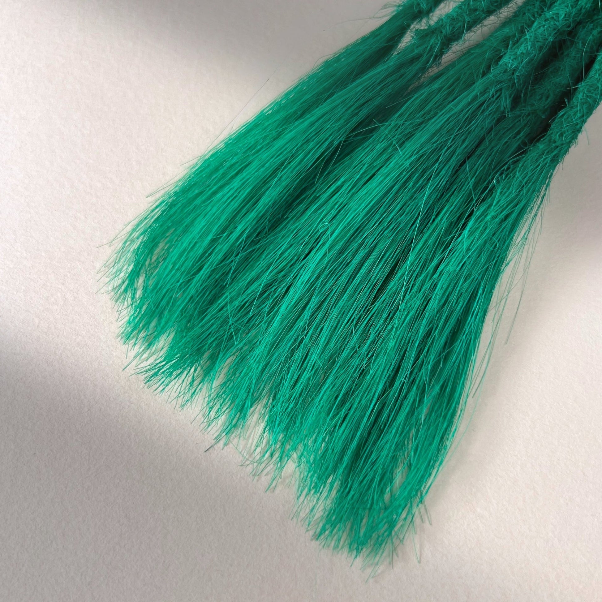 Tip detail of straight loc extensions with open ends in Emerald Green.