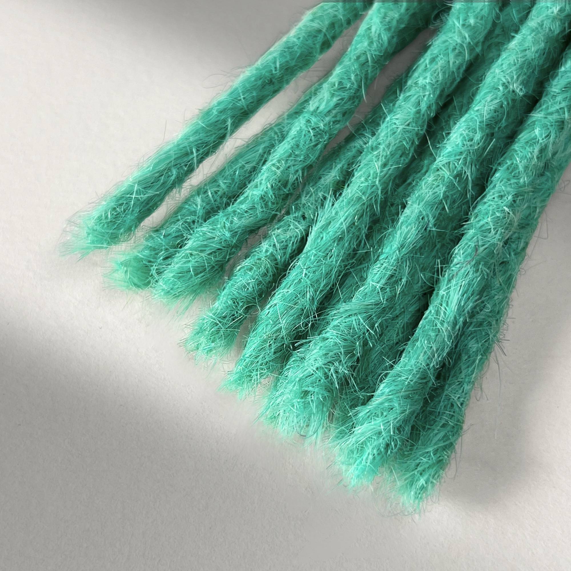 Tip detail of straight loc extensions with blunt ends in Pastel Emerald Green.