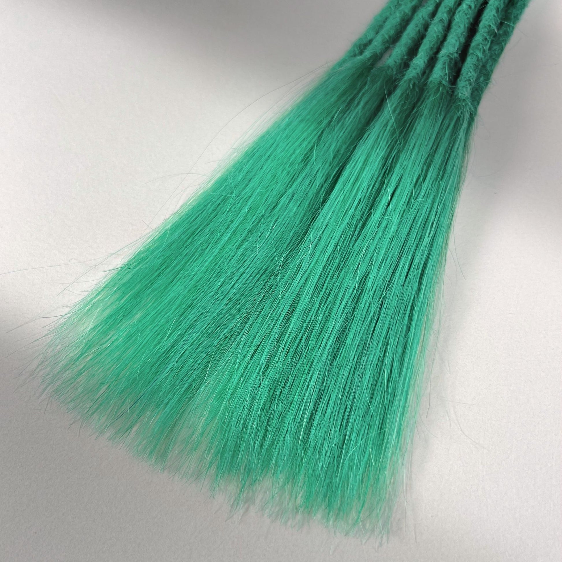 Tip detail of straight loc extensions with long loose ends in Pastel Emerald Green.