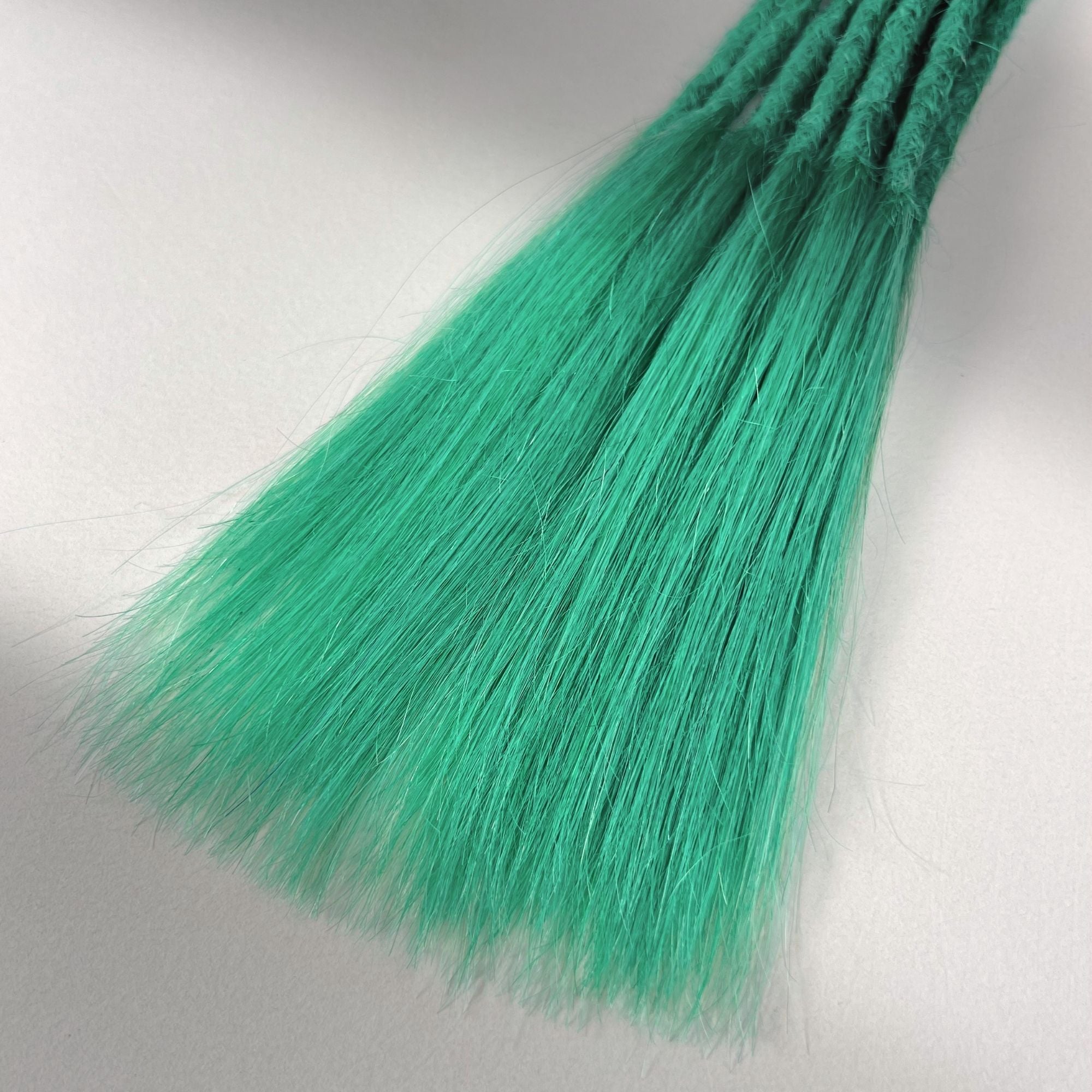 Tip detail of straight loc extensions with long loose ends in Pastel Emerald Green.