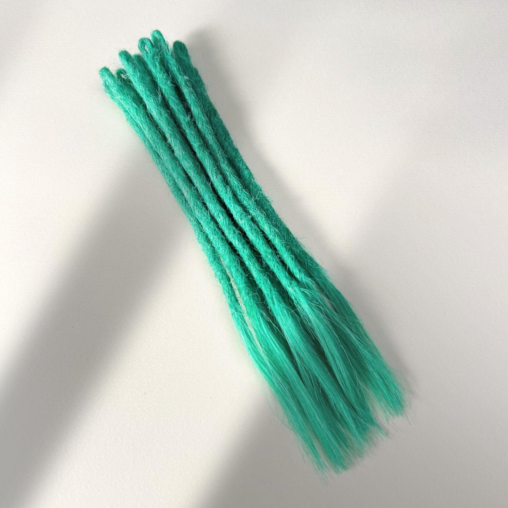Full view of temporary single-ended straight loc extensions with open ends in Pastel Emerald Green.