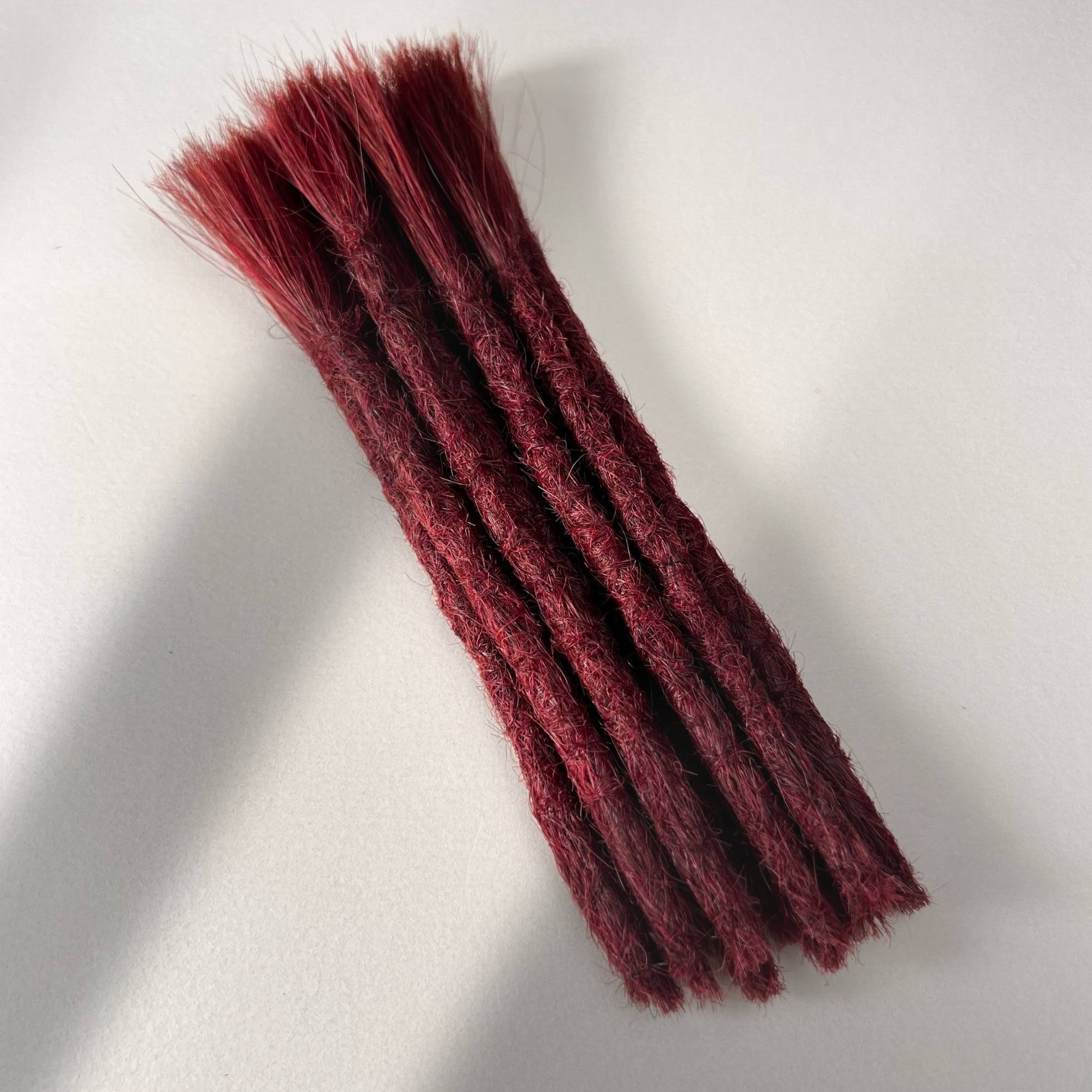 Full view of permanent straight loc extensions with blunt ends in Deep Garnet Red.