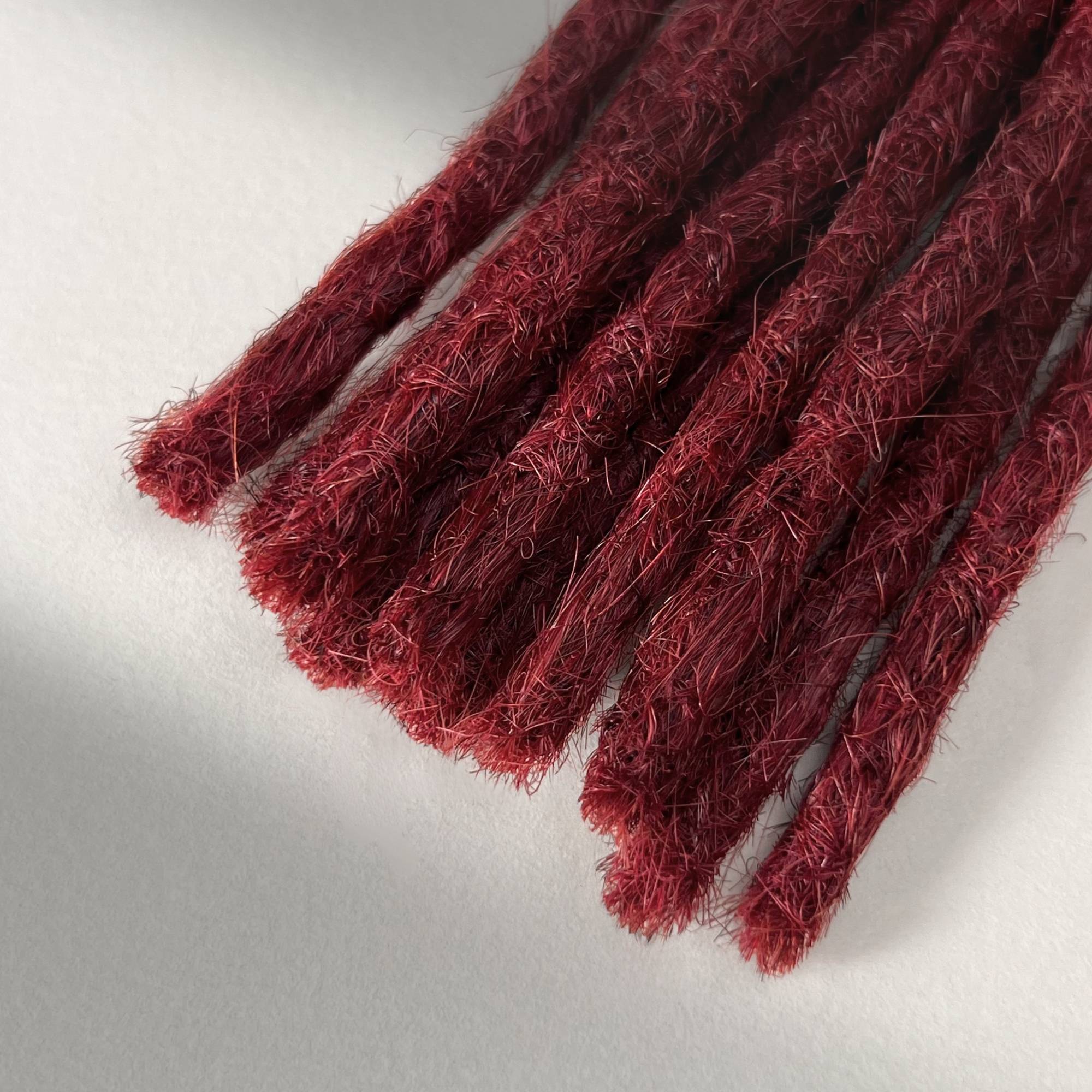 Tip detail of straight loc extensions with blunt ends in Deep Garnet Red.