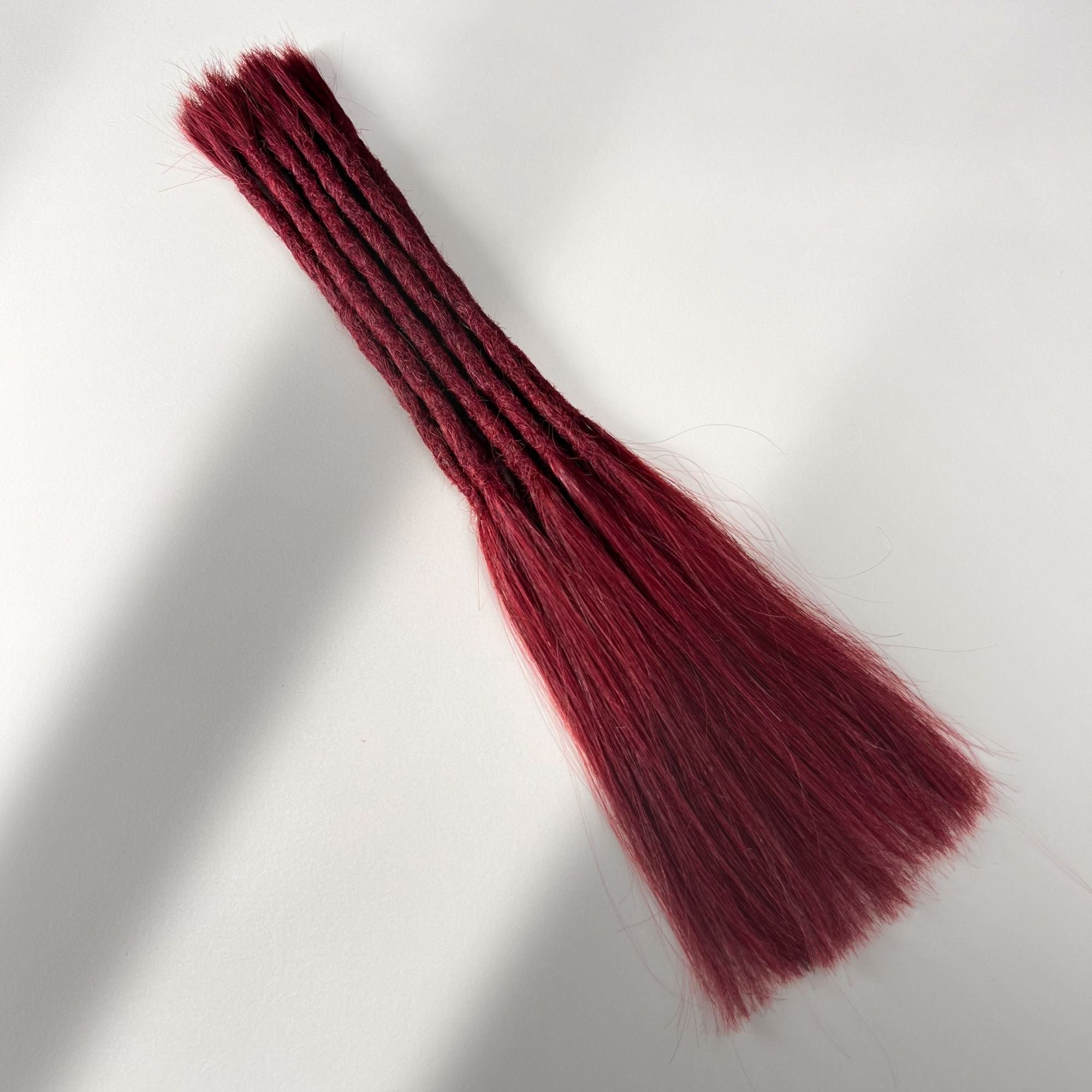 Full view of permanent straight loc extensions with long loose ends in Deep Garnet Red.