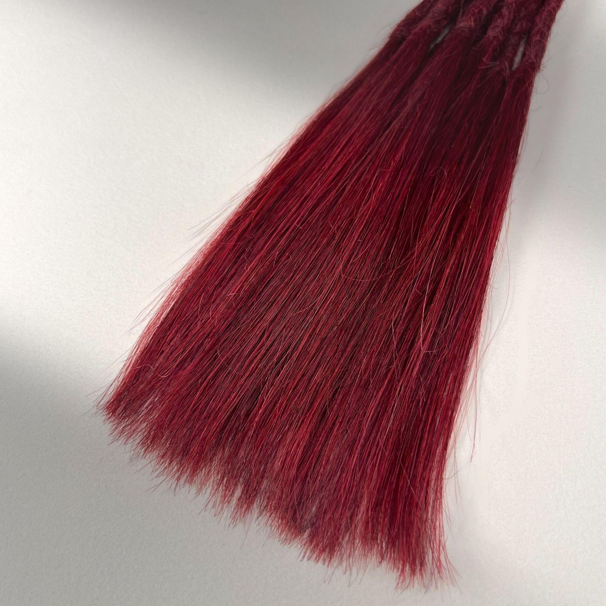 Tip detail of straight loc extensions with long loose ends in Deep Garnet Red.