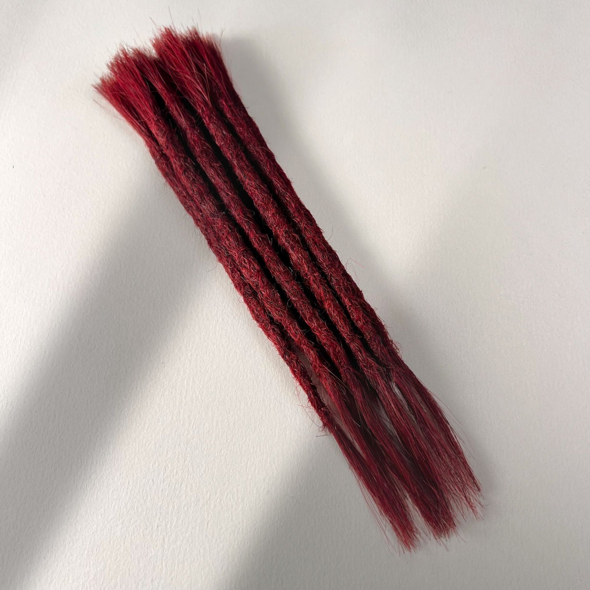 Full view of permanent straight loc extensions with open ends in Deep Garnet Red.