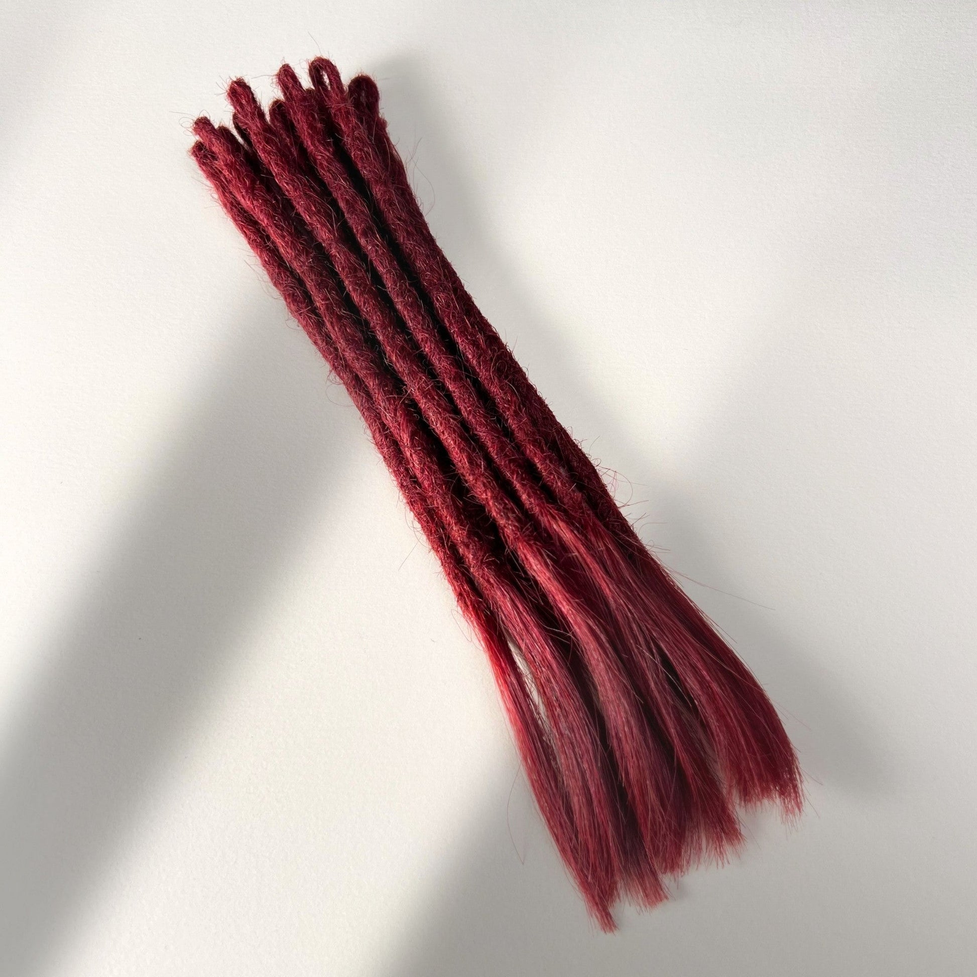 Full view of temporary single-ended straight loc extensions with open ends in Deep Garnet Red.