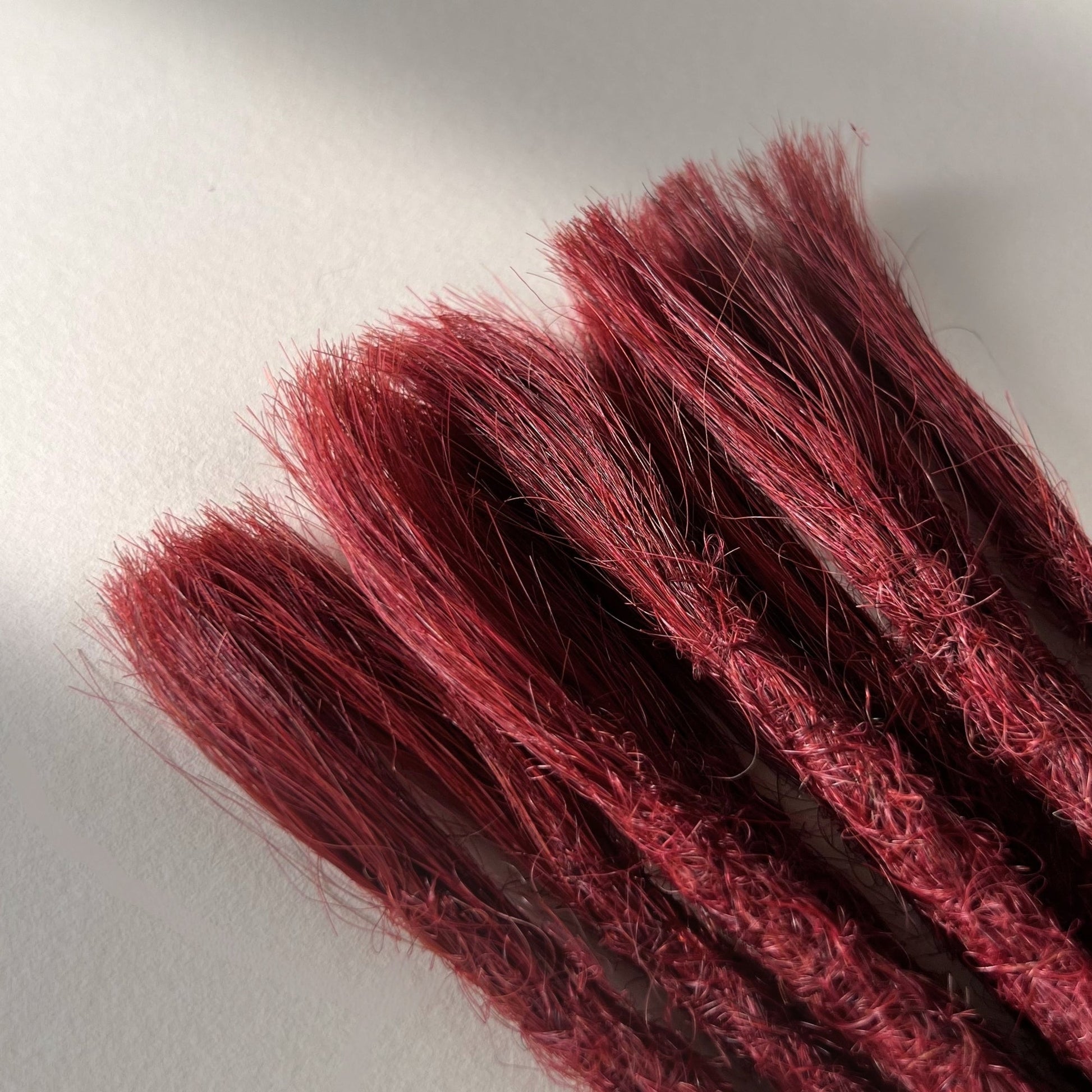 Connection point of permanent straight loc extensions in Deep Garnet Red.