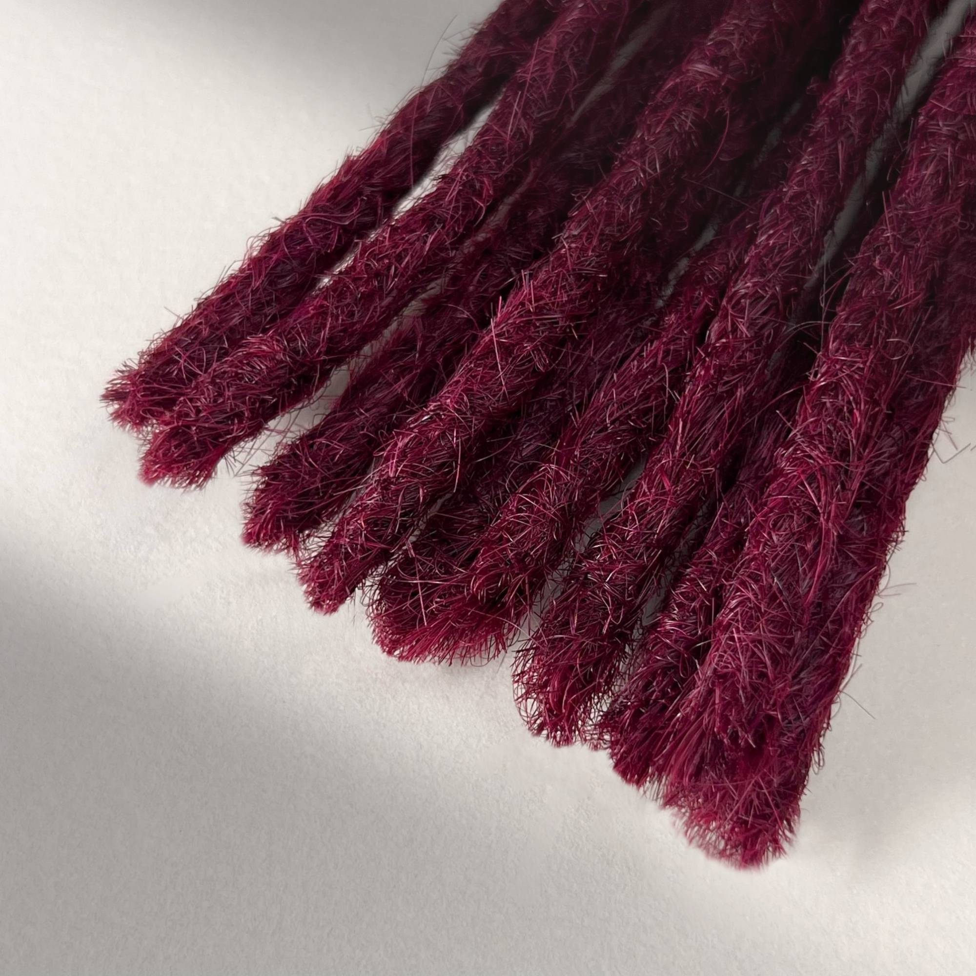 Tip detail of straight loc extensions with blunt ends in Dark Cherry Red.