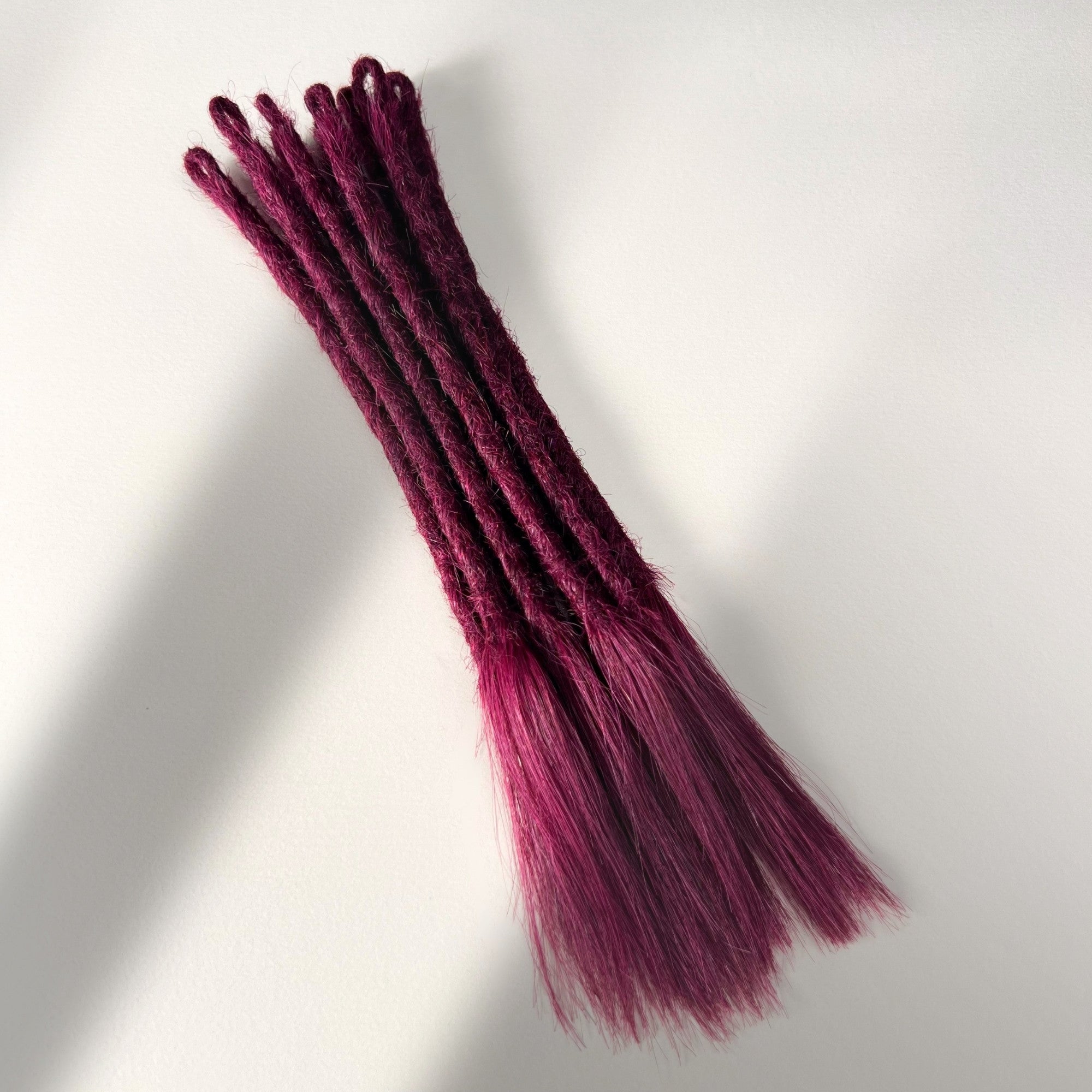 Full view of temporary single-ended straight loc extensions with open ends in Dark Cherry Red.