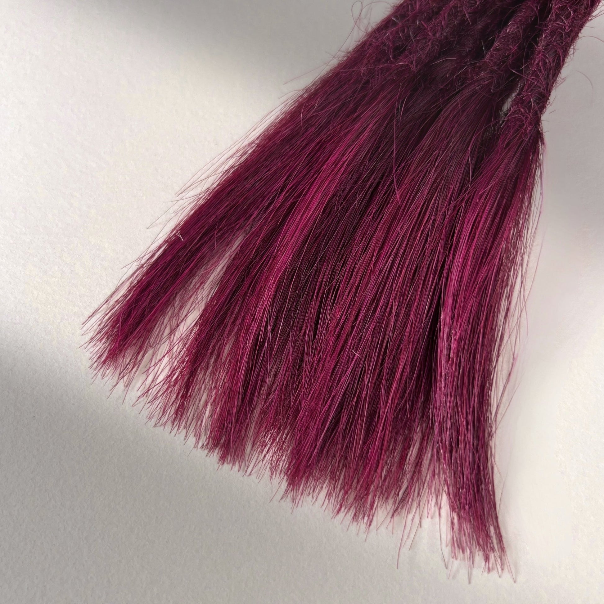 Tip detail of straight loc extensions with open ends in Dark Cherry Red.