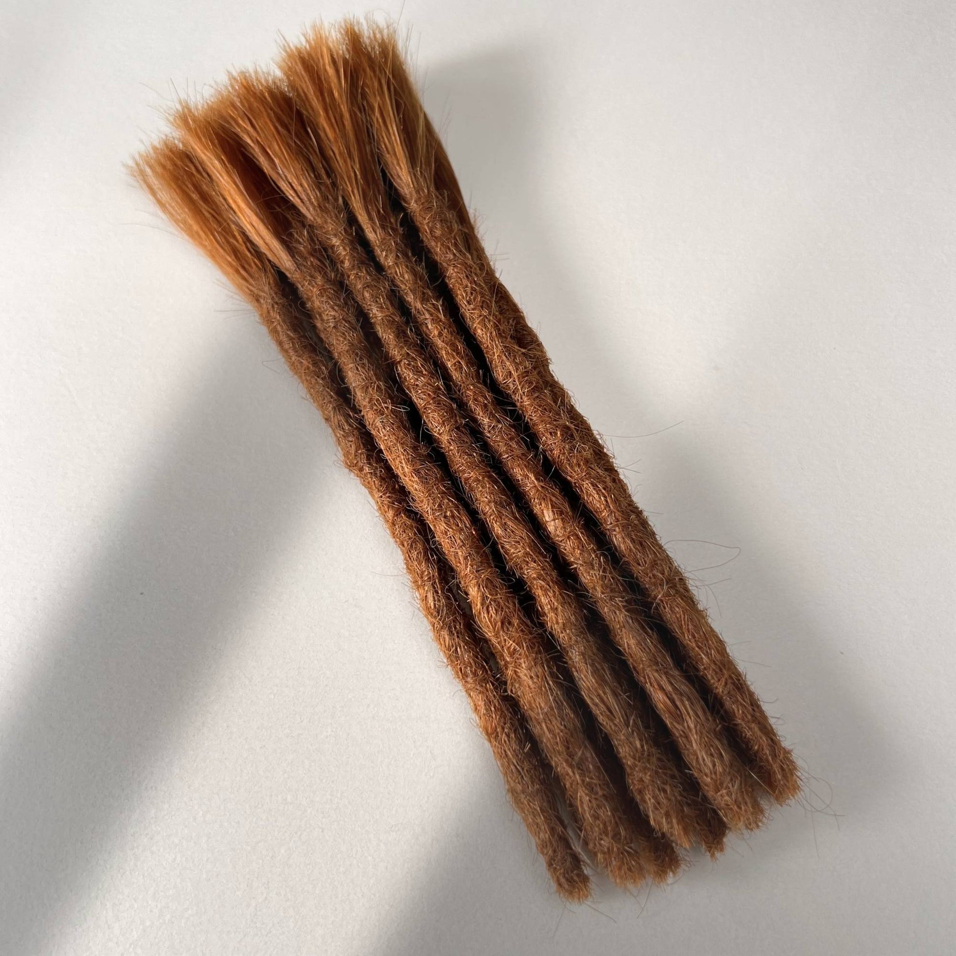 Full view of permanent straight loc extensions with blunt ends in Burnt Copper.