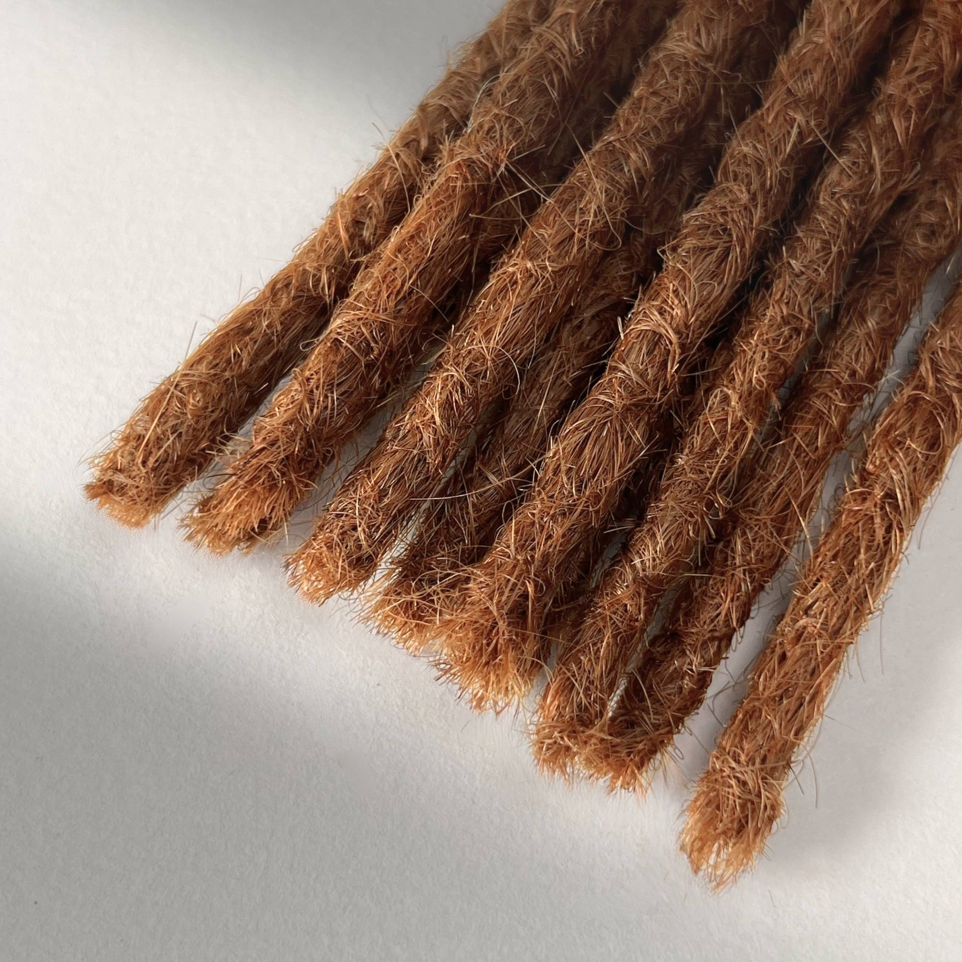 Tip detail of straight loc extensions with blunt ends in Burnt Copper.
