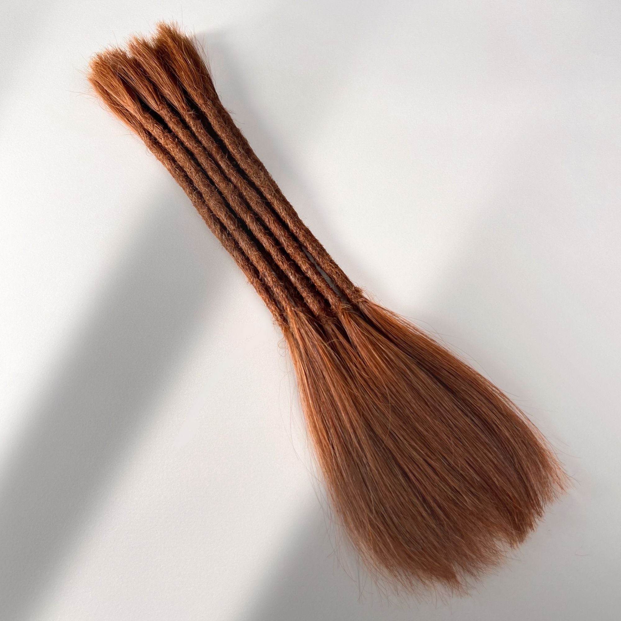 Full view of permanent straight loc extensions with long loose ends in Burnt Copper.