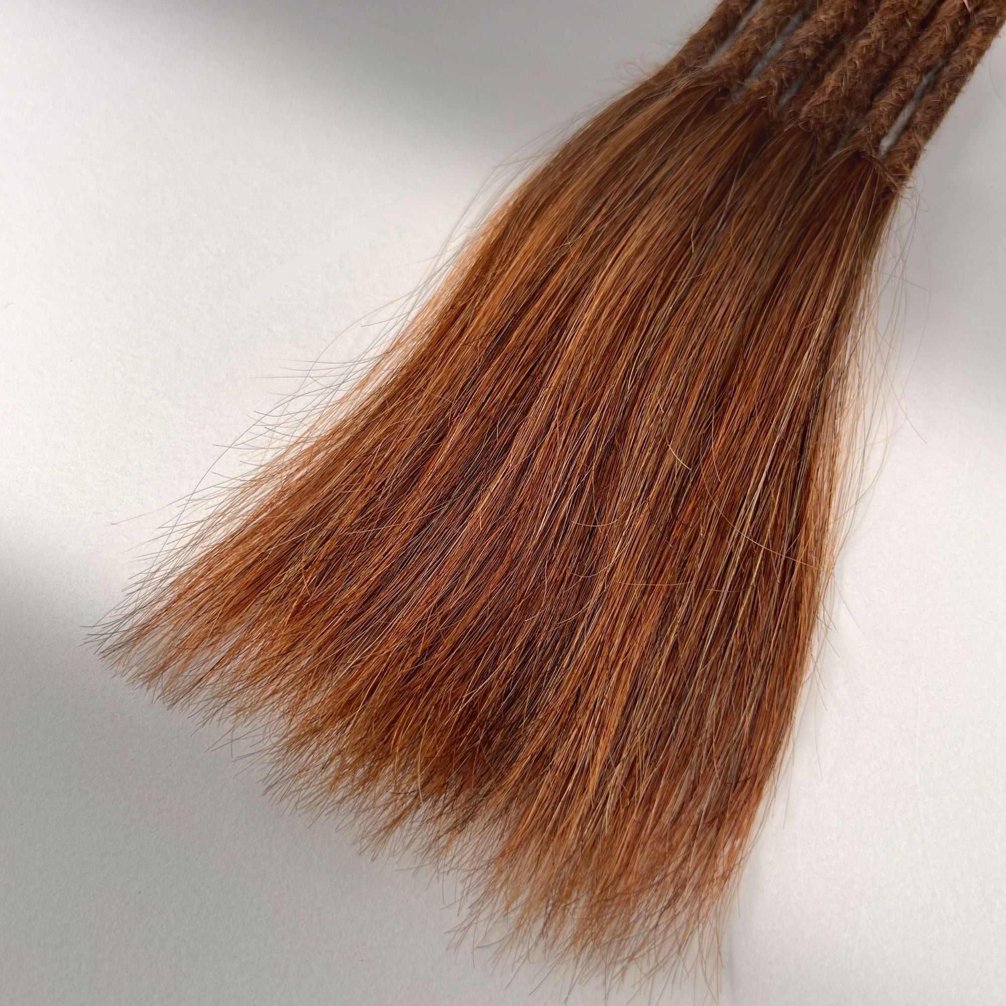 Tip detail of straight loc extensions with long loose ends in Burnt Copper.