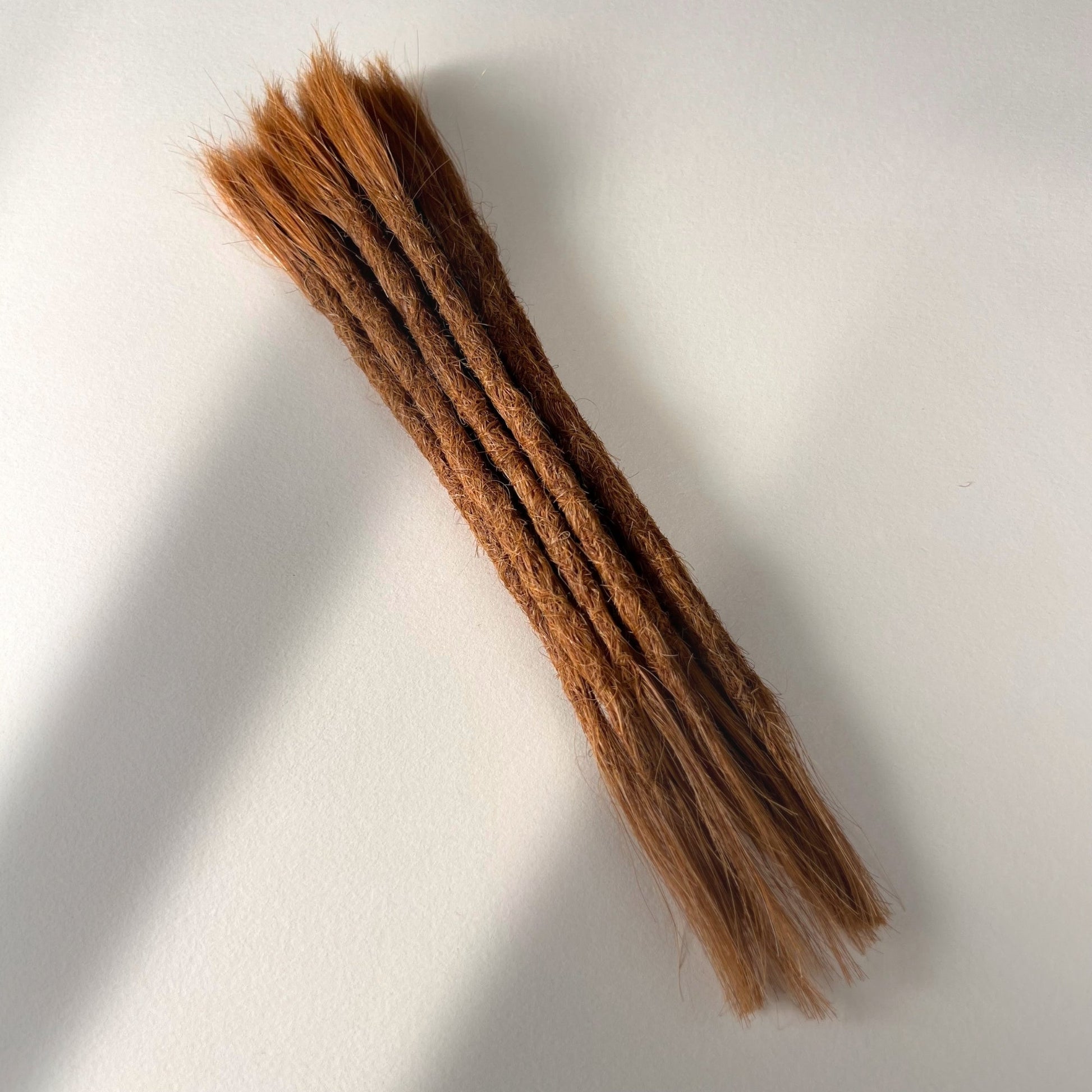 Full view of permanent straight loc extensions with open ends in Burnt Copper.