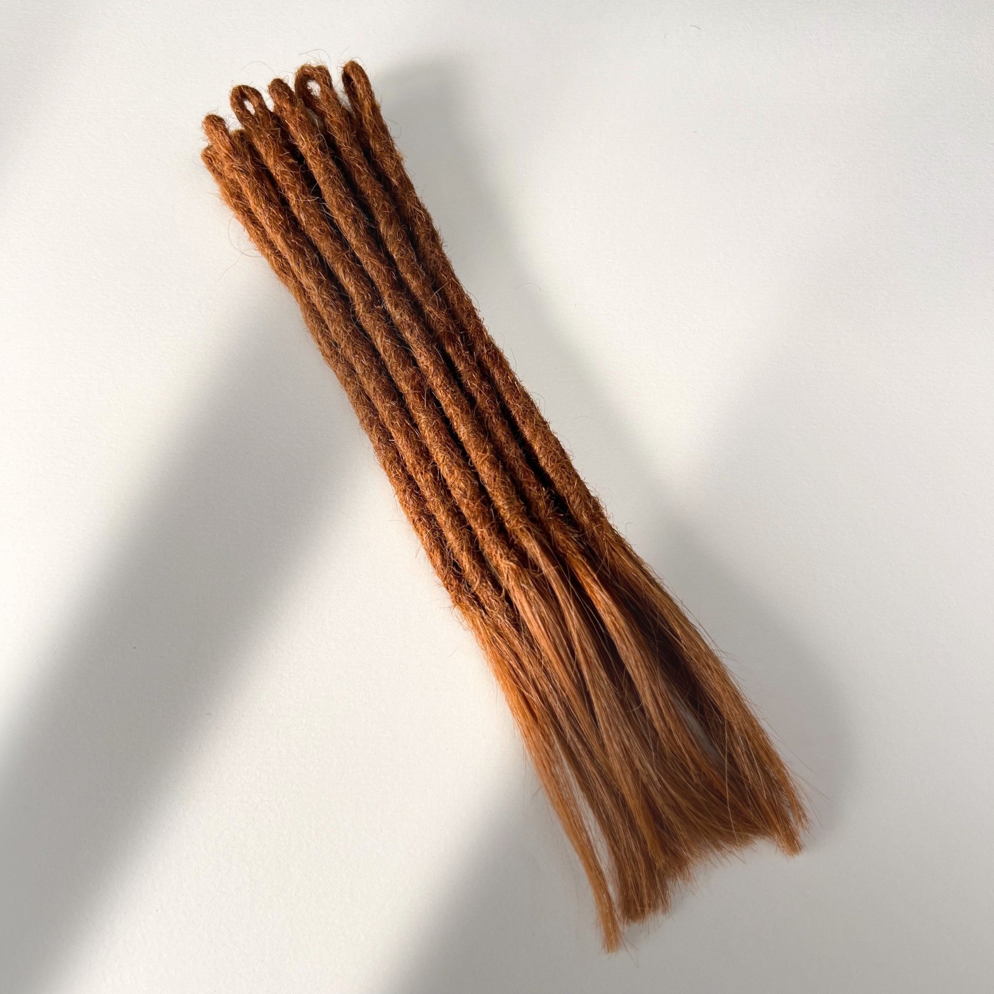 Full view of temporary single-ended straight loc extensions with open ends in Burnt Copper.