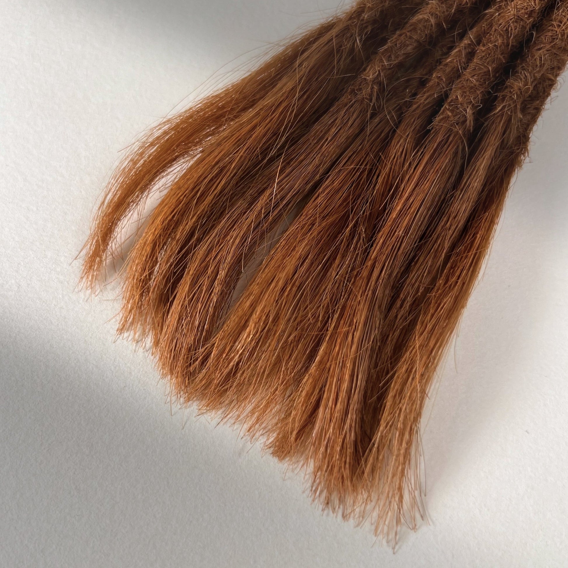 Tip detail of straight loc extensions with open ends in Burnt Copper.
