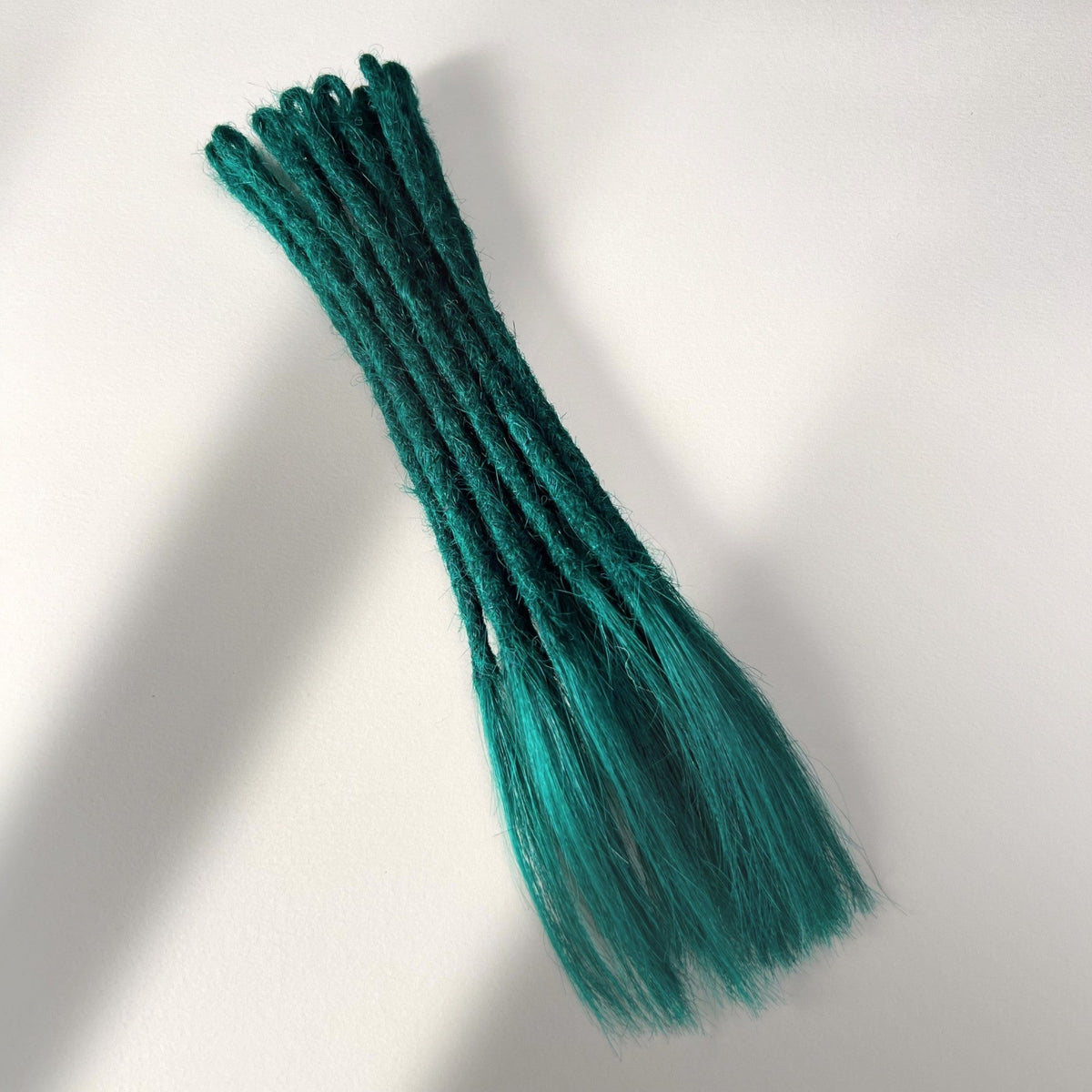 Full view of temporary single-ended straight loc extensions with open ends in Forest Green.